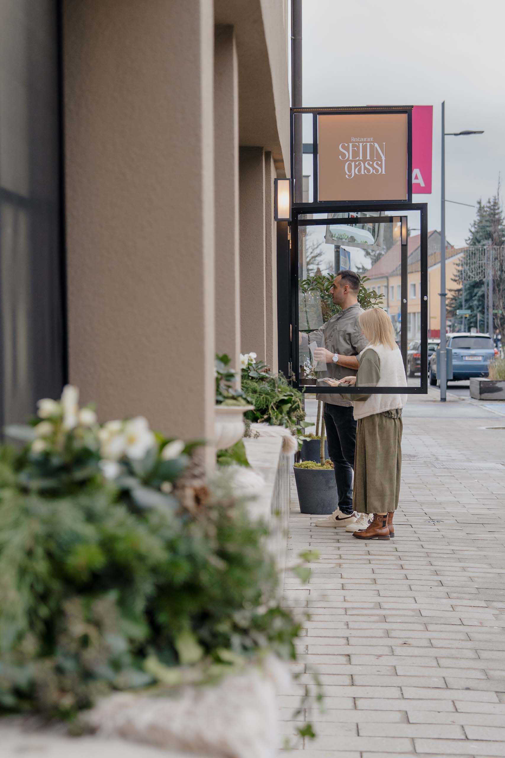 Paar betrachtet Menü an der Hochzeitslocation, umgeben von eleganter Dekoration, ideal für Hochzeitsträume.