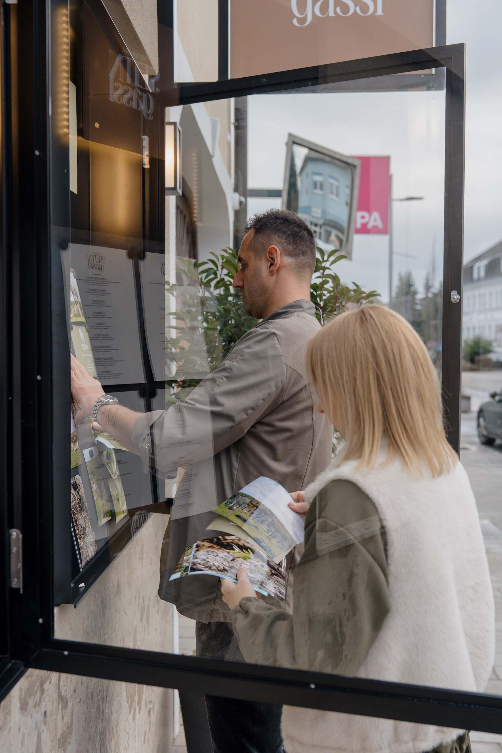 Paar besucht Hochzeitstraum-Location, studiert Broschüren und Aushänge für perfekte Hochzeitsplanung.