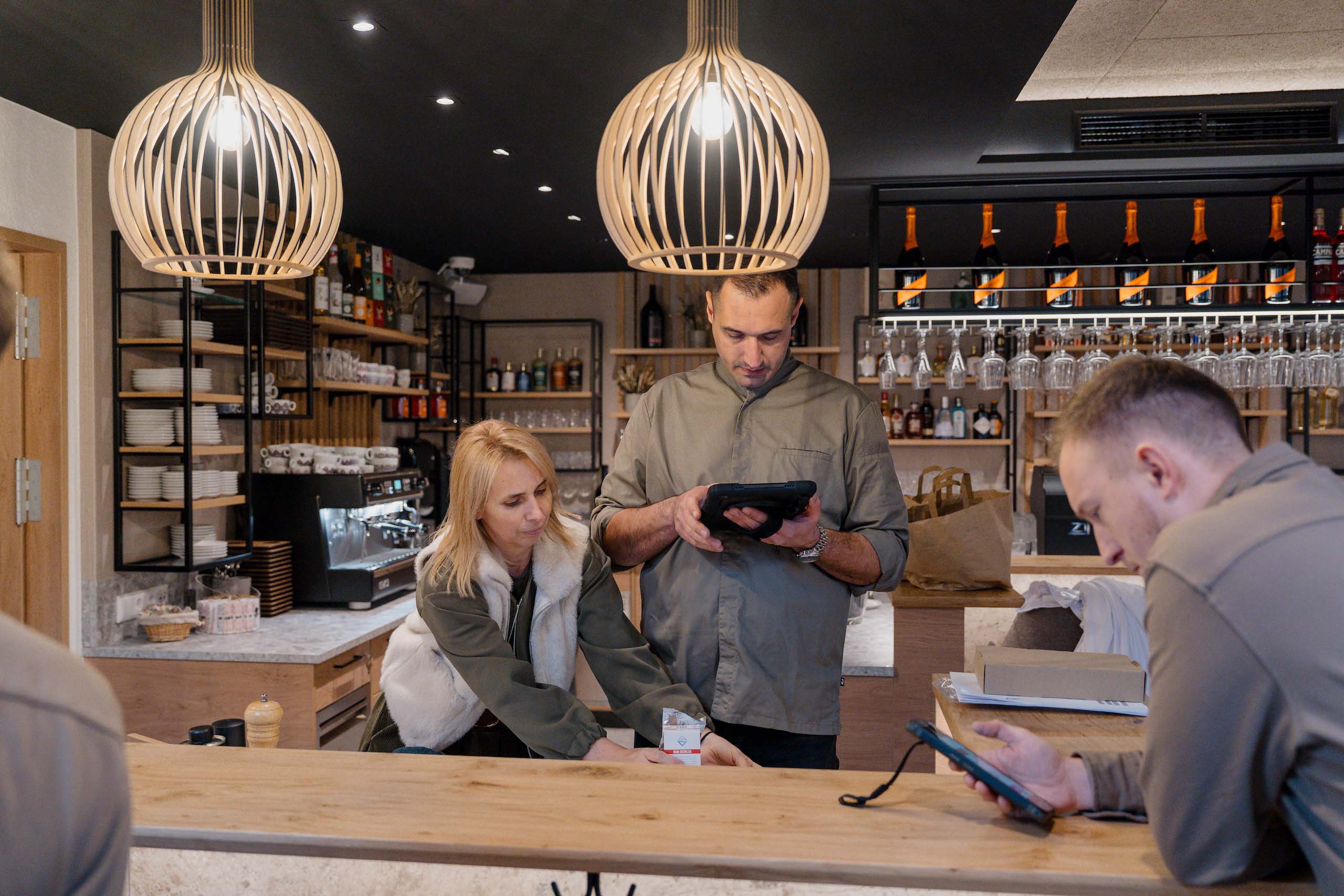 Modernes Café-Personal in Hochzeitslocation am Tresen berät sich, ideal für Ihre Traumhochzeit.