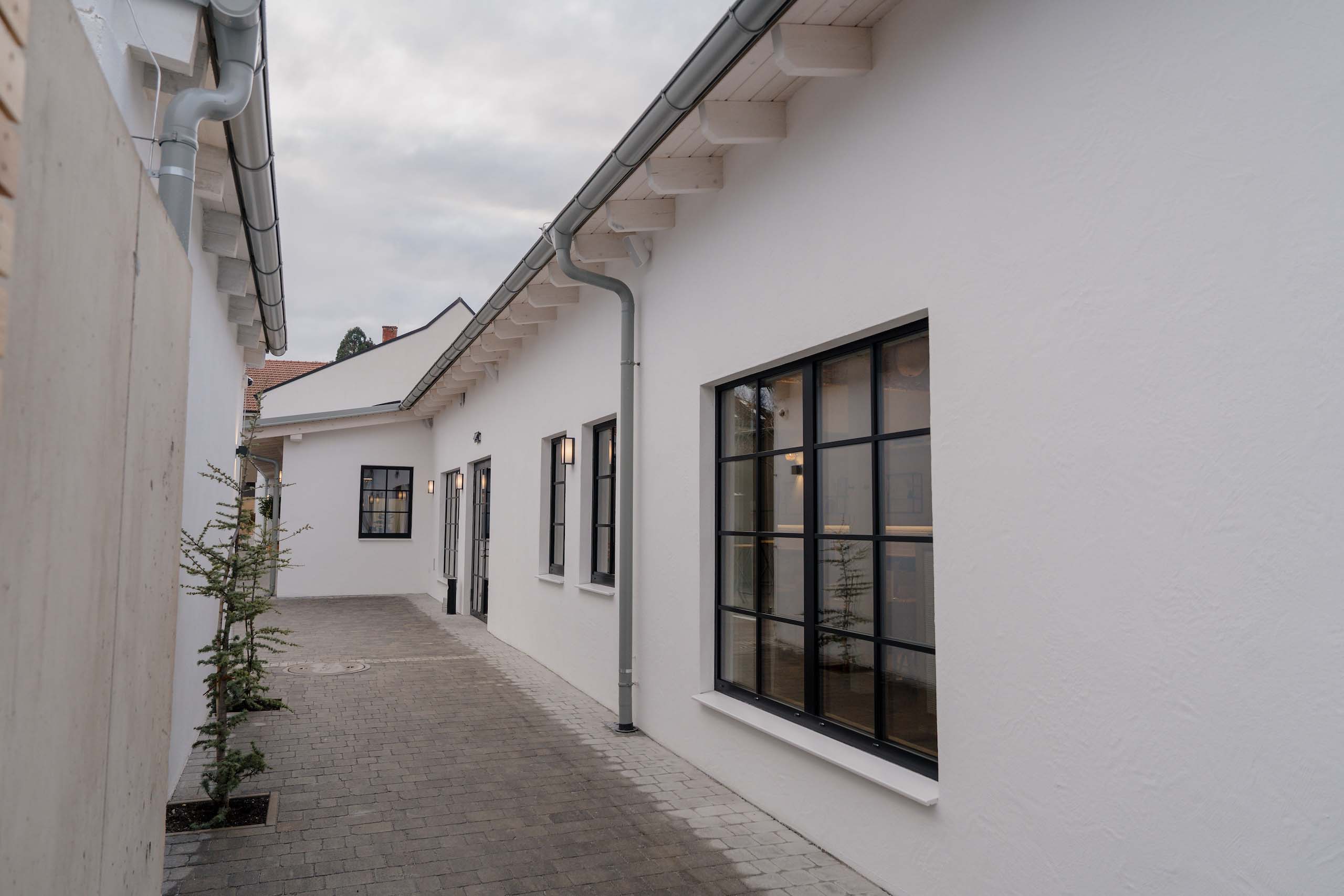 Moderner, eleganter Innenhof einer Hochzeitslocation mit weißen Gebäuden, ideal für unvergessliche Hochzeitsträume.