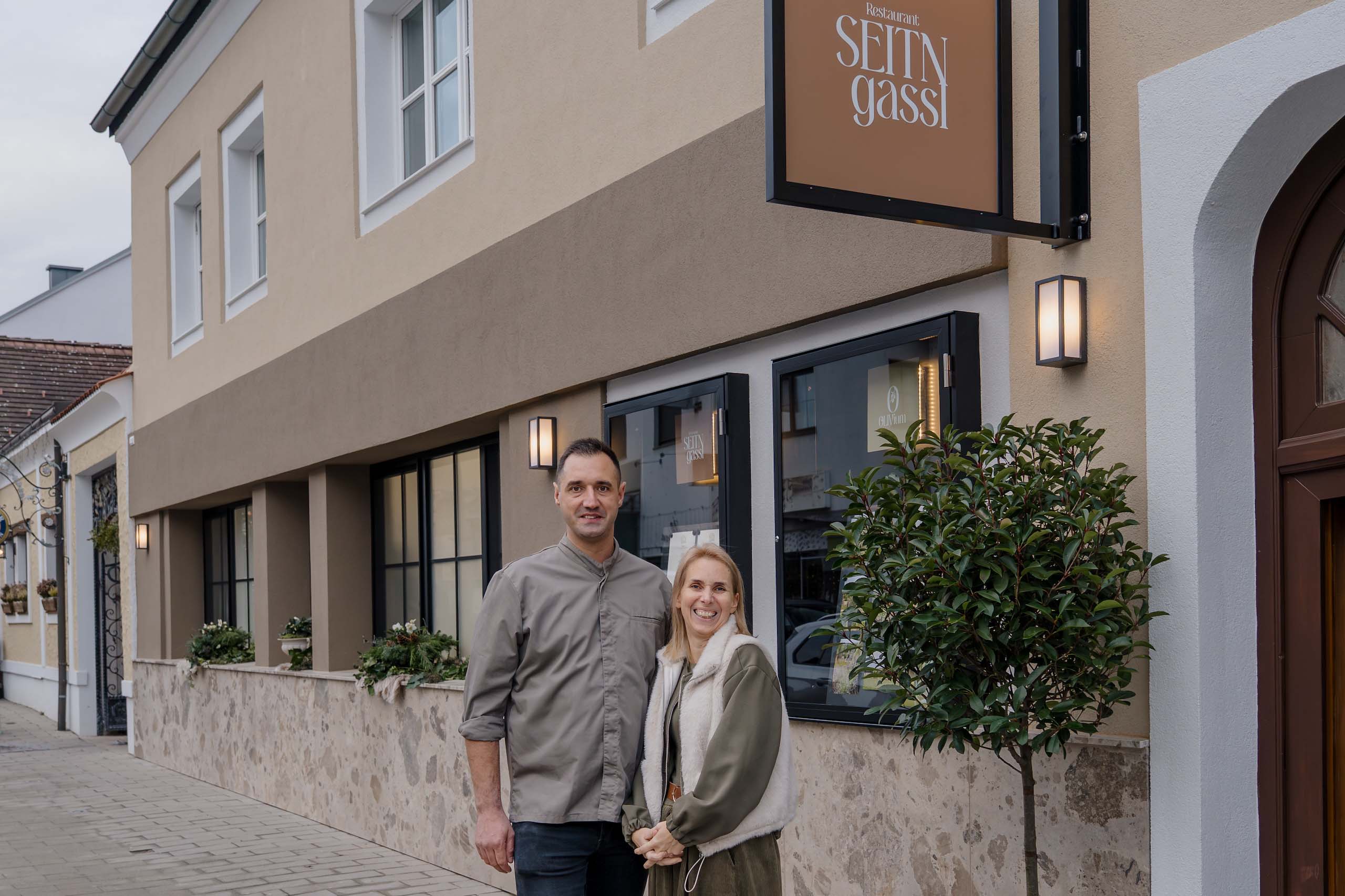 Paar vor Restaurant „Seiten Gassl“ als stilvolle Hochzeitslocation, ideale Kulisse für den Hochzeitstraum-Moment.