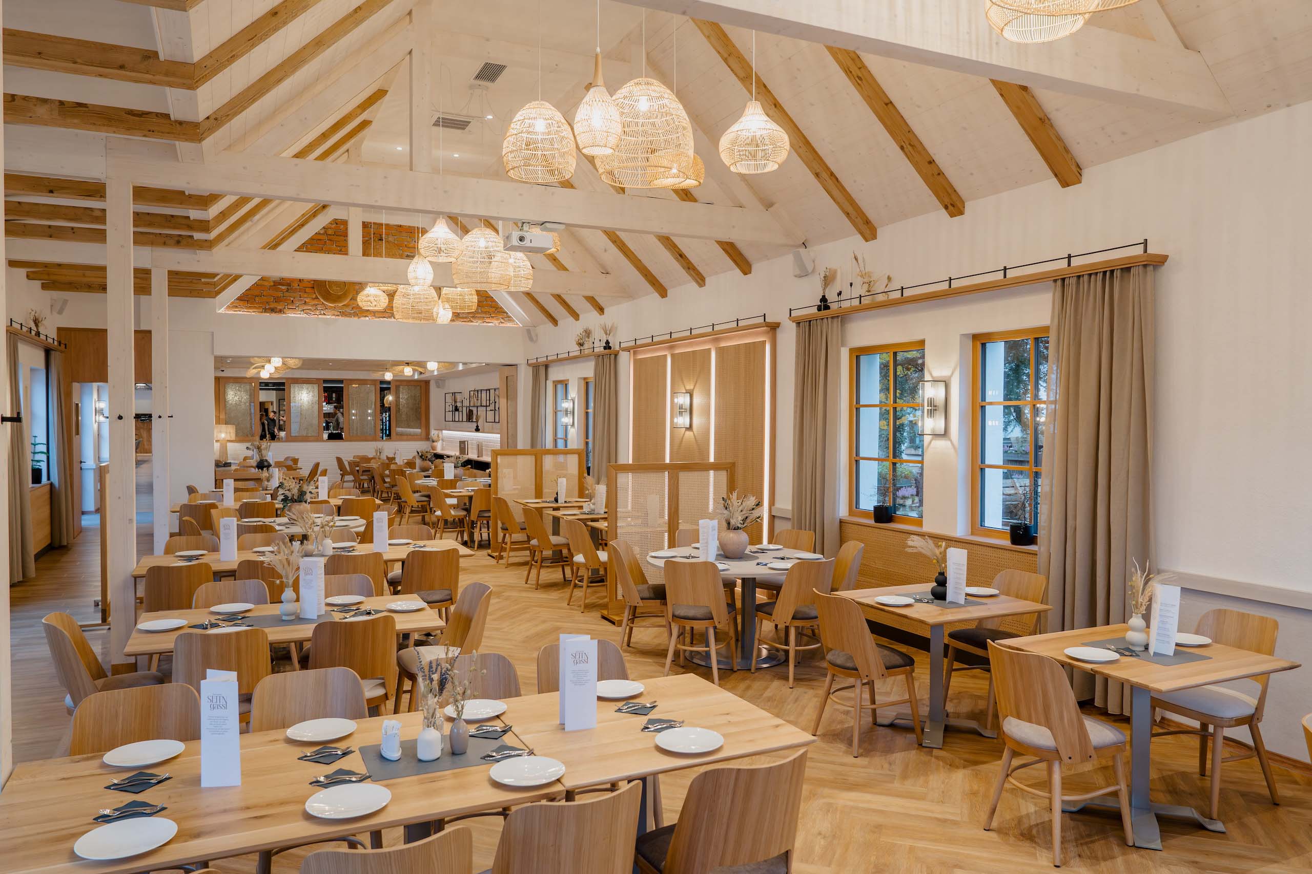 Elegante, helle Hochzeitslocation mit Holzmöbeln und modernen Lampen, perfekt für einen Hochzeitstraum in stilvollem Ambiente.