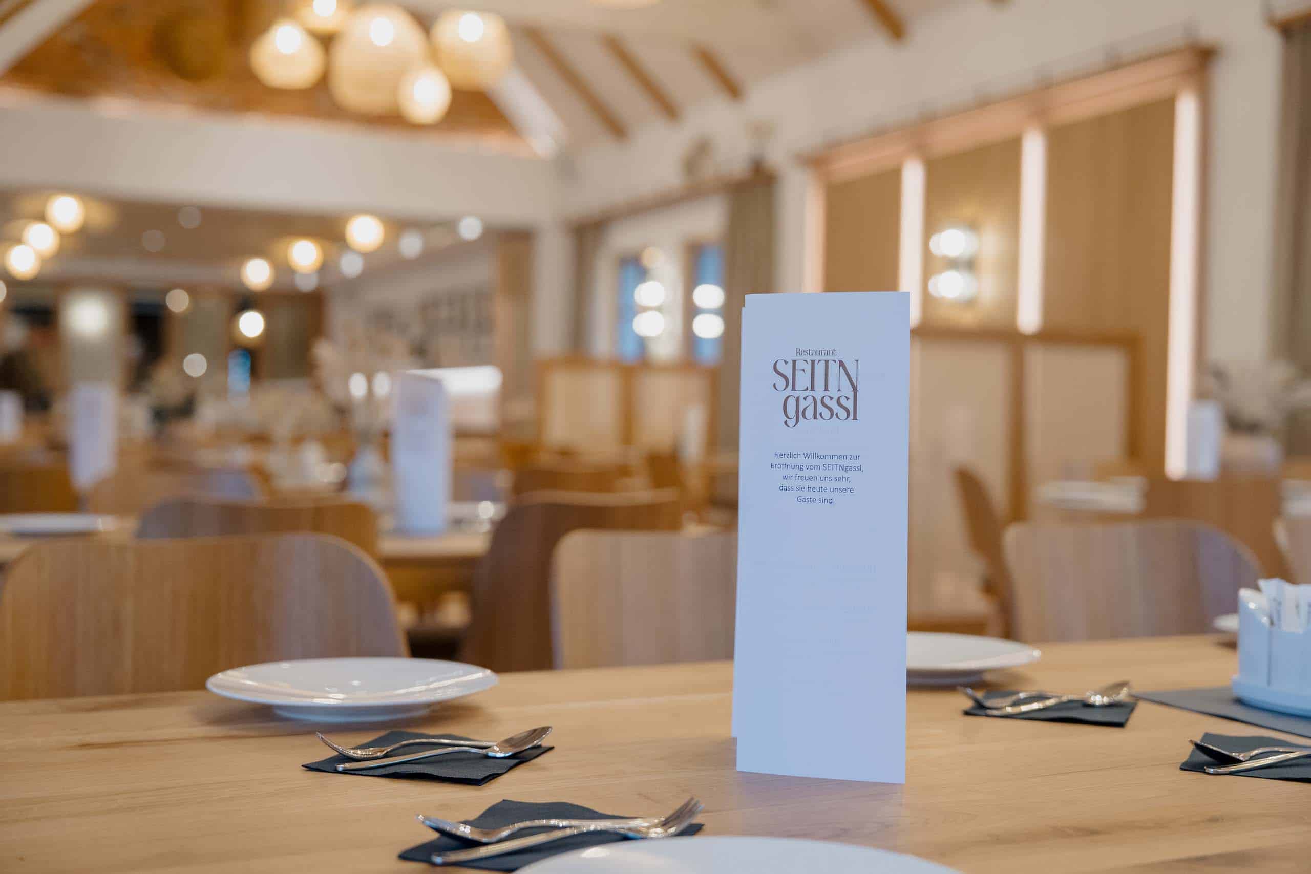 Elegante Tischdekoration in heller Hochzeitslocation mit Menükarte, ideal für Ihre Feiern