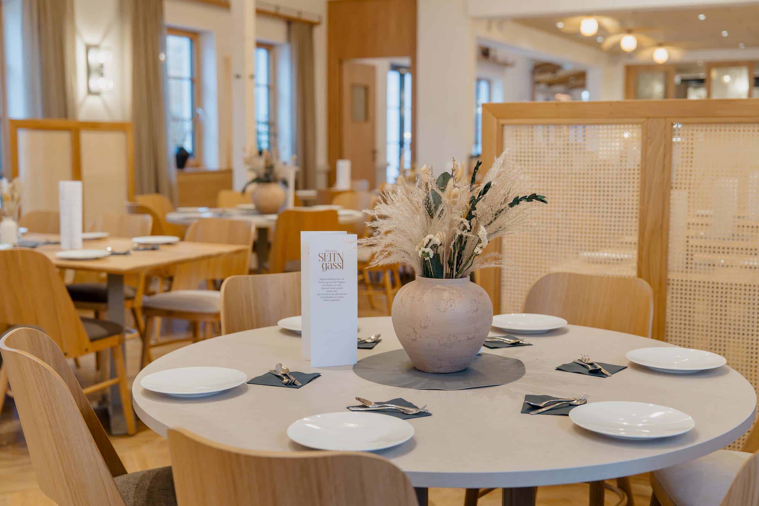 Elegante Hochzeitstafel in stilvoller Location, dekoriert mit Blumengesteck und Geschirr, perfekt für Ihren Hochzeitstraum.