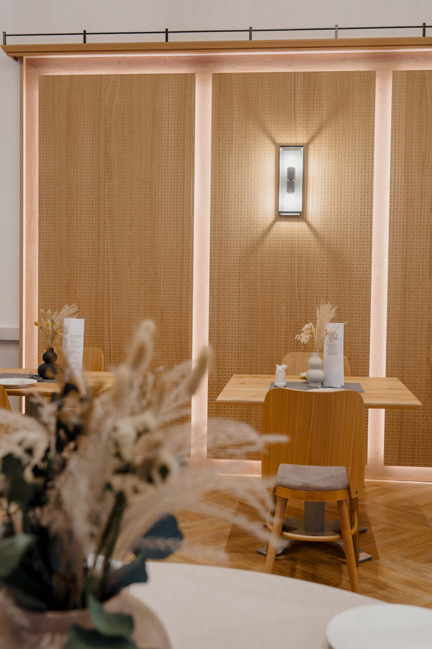 Elegante Hochzeitstische mit natürlichem Dekor in stilvollem, modernem Raum, ideal für eine Hochzeitslocation.