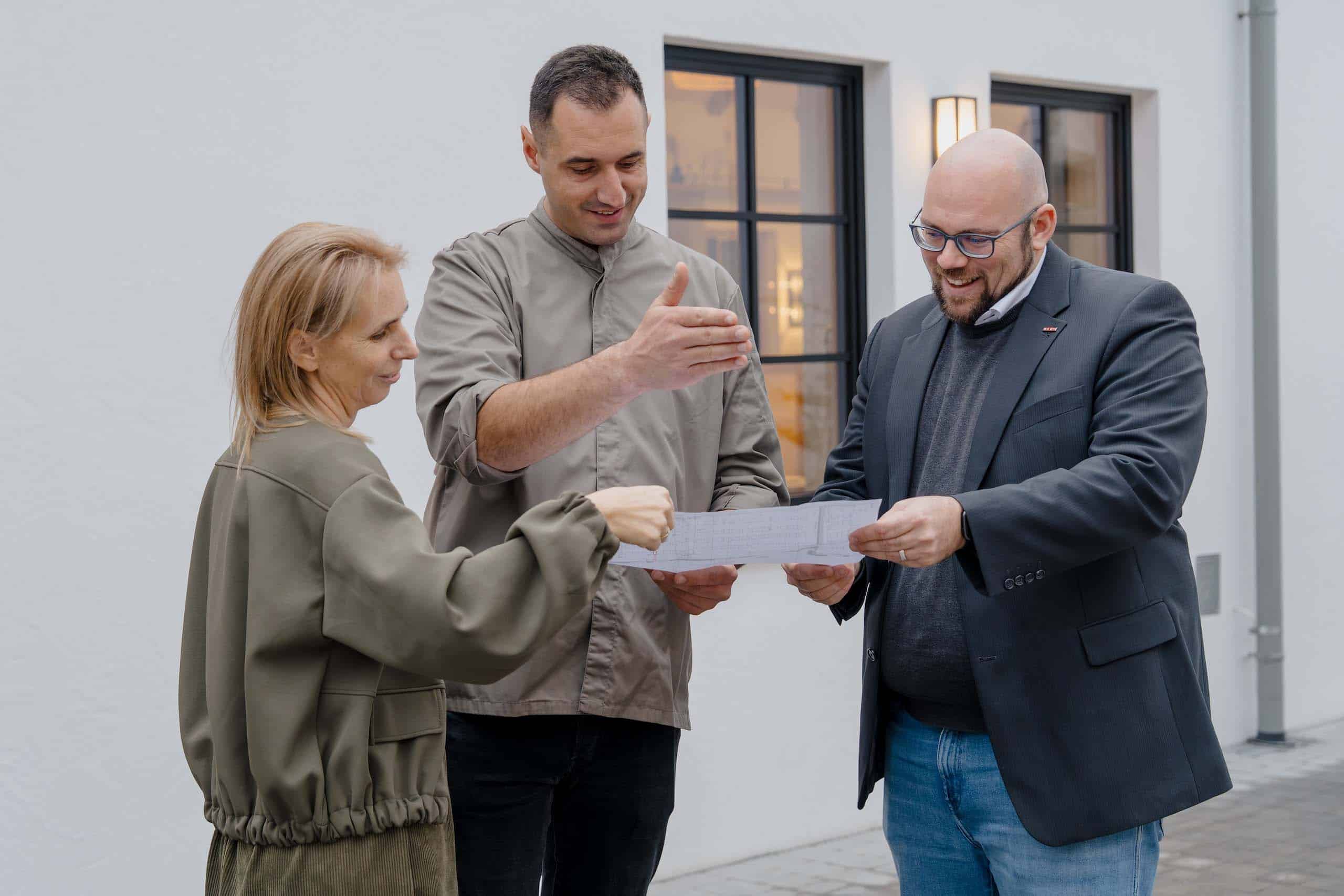 Personen besprechen Hochzeitspläne vor einer eleganten Hochzeitslocation, perfekte Kulisse für den Hochzeitstraum.