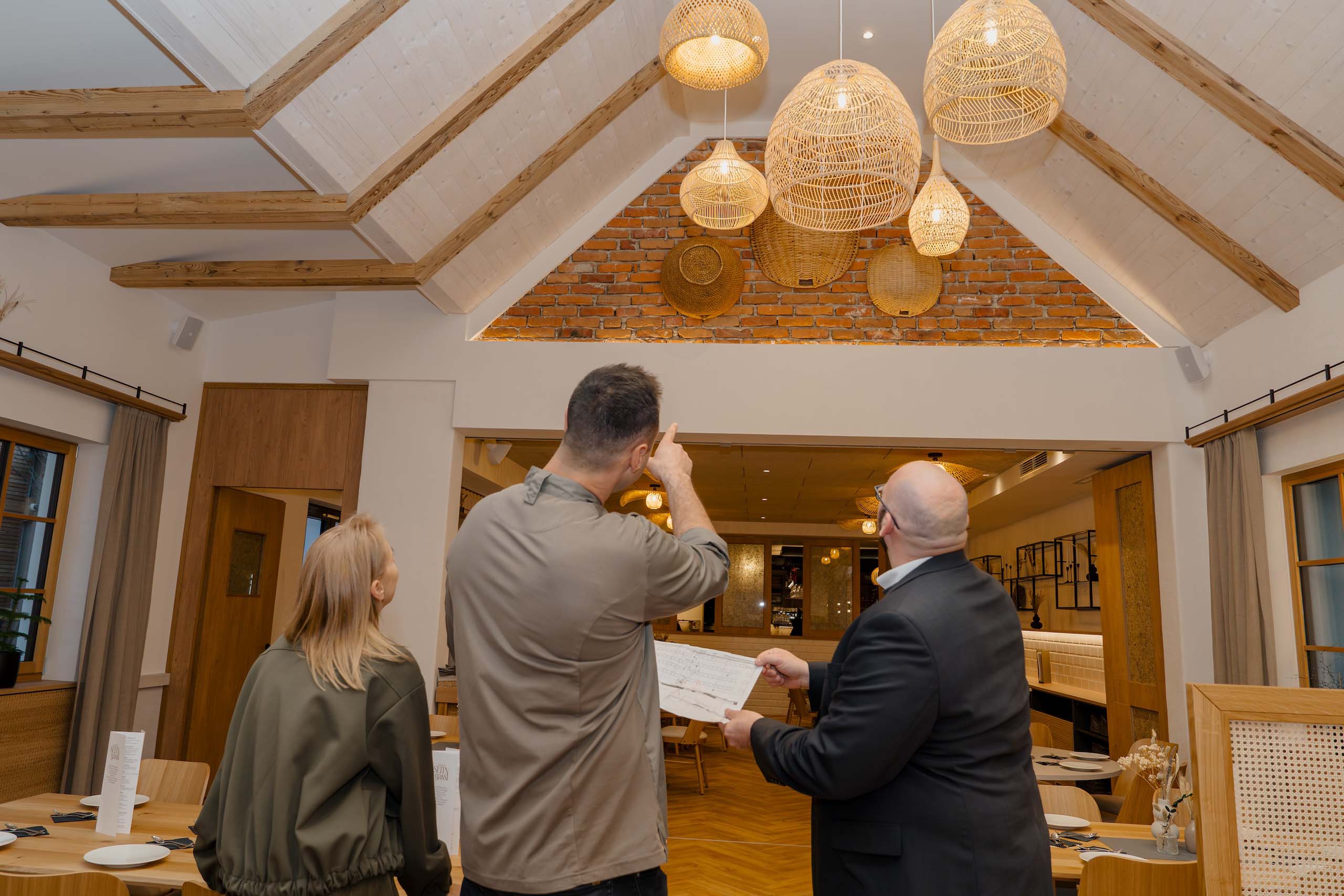 Paar besichtigt rustikale Hochzeitslocation mit Holzbalken und Körbe als Dekoration – ideal für einen Hochzeitstraum.