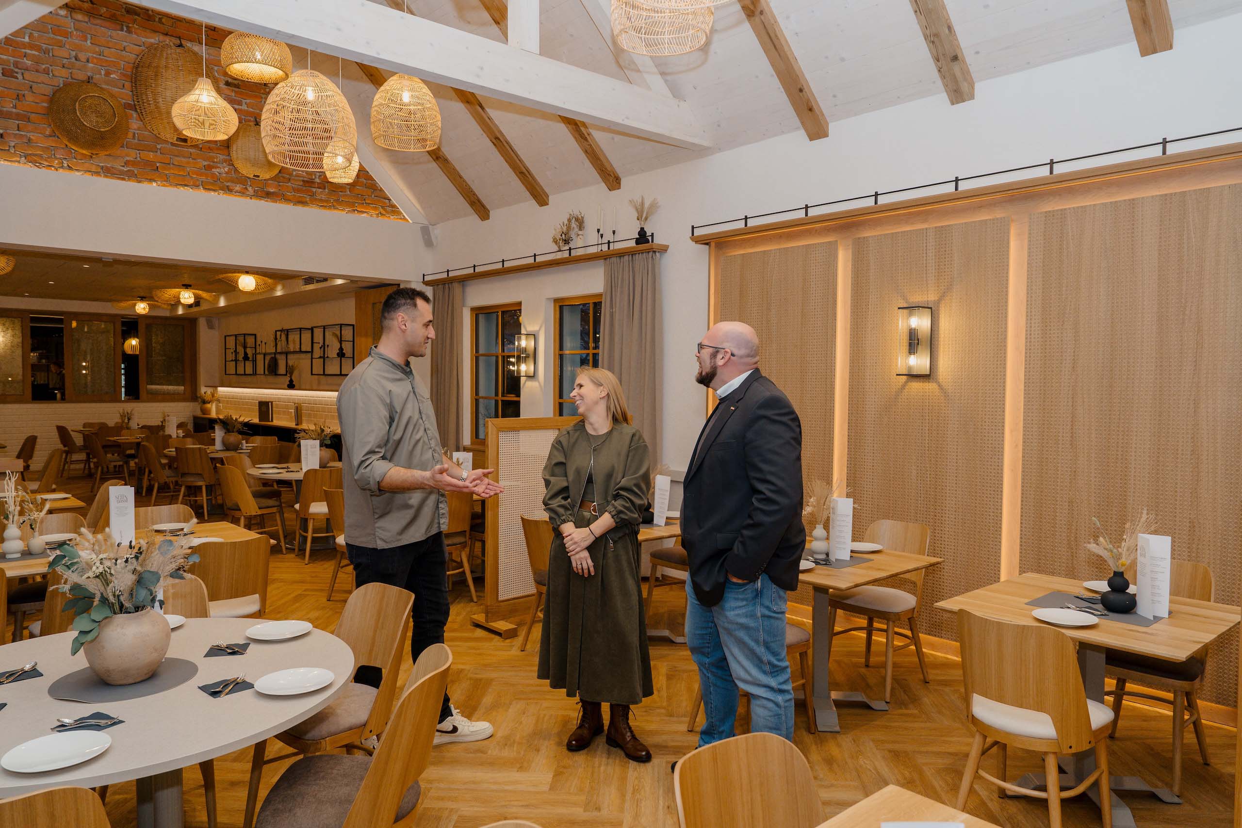 Elegantes Restaurant mit gemütlicher Atmosphäre, ideal als Hochzeitslocation bei Hochzeitstraum, drei Personen im Gespräch.