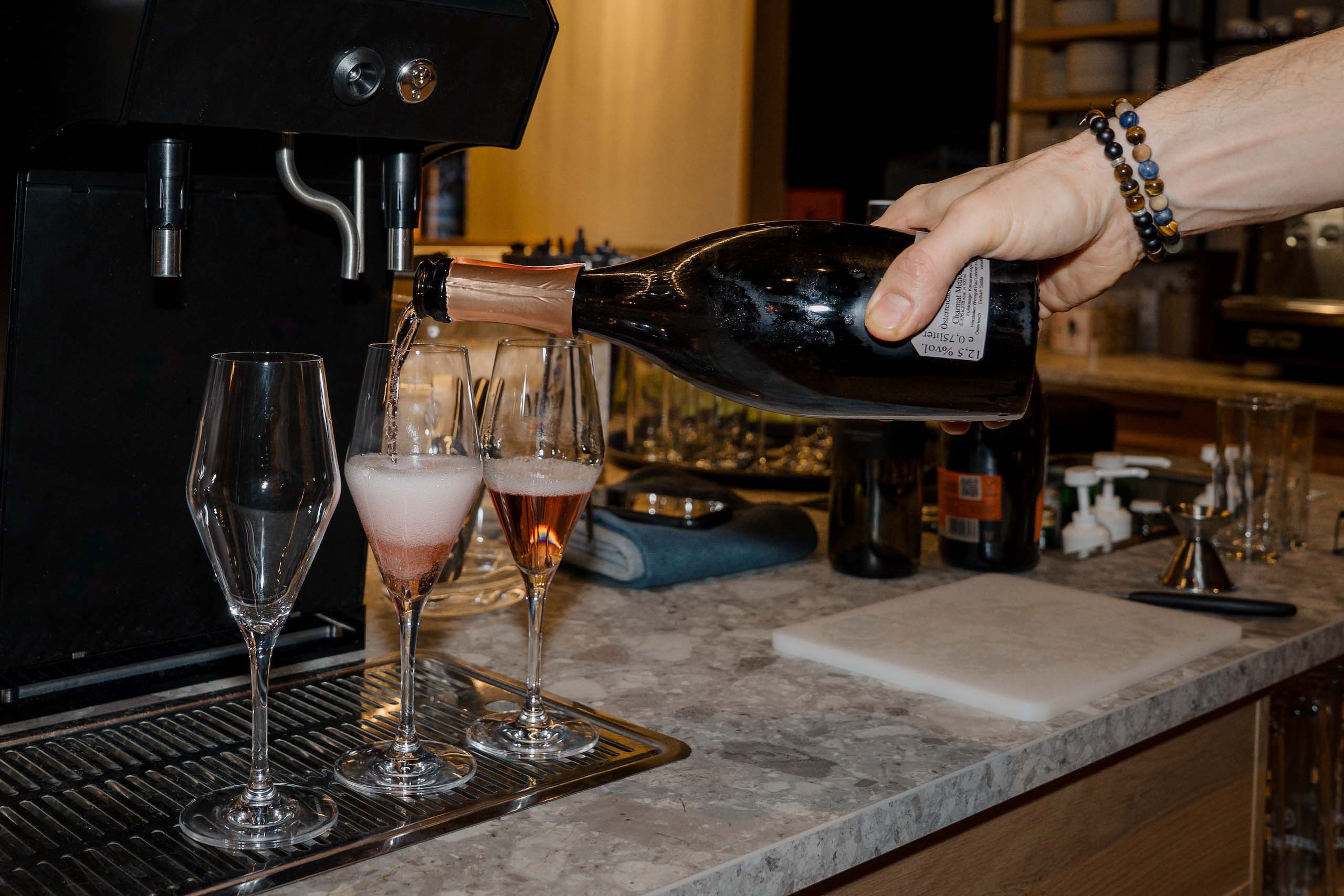 Person gießt Sekt in Gläser bei Hochzeitsempfang, unterstreicht elegante Atmosphäre der Hochzeitslocation.