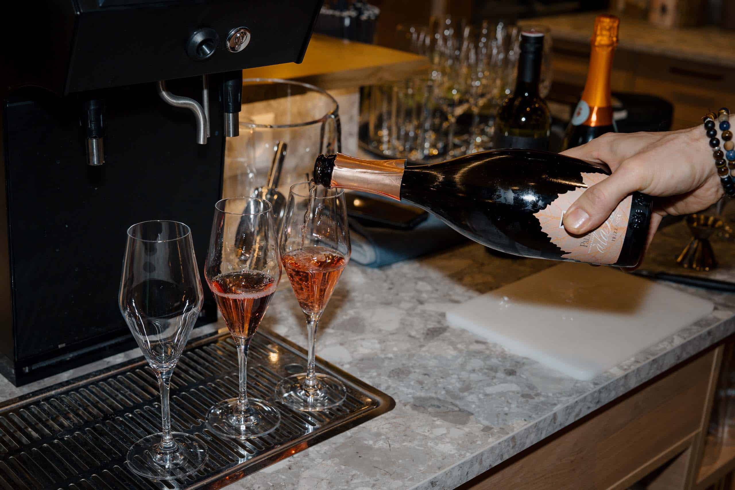 Hand schenkt stilvoll Rosé-Champagner in Gläser ein, ideale Hochzeitslocation für einen unvergesslichen Hochzeitstraum.