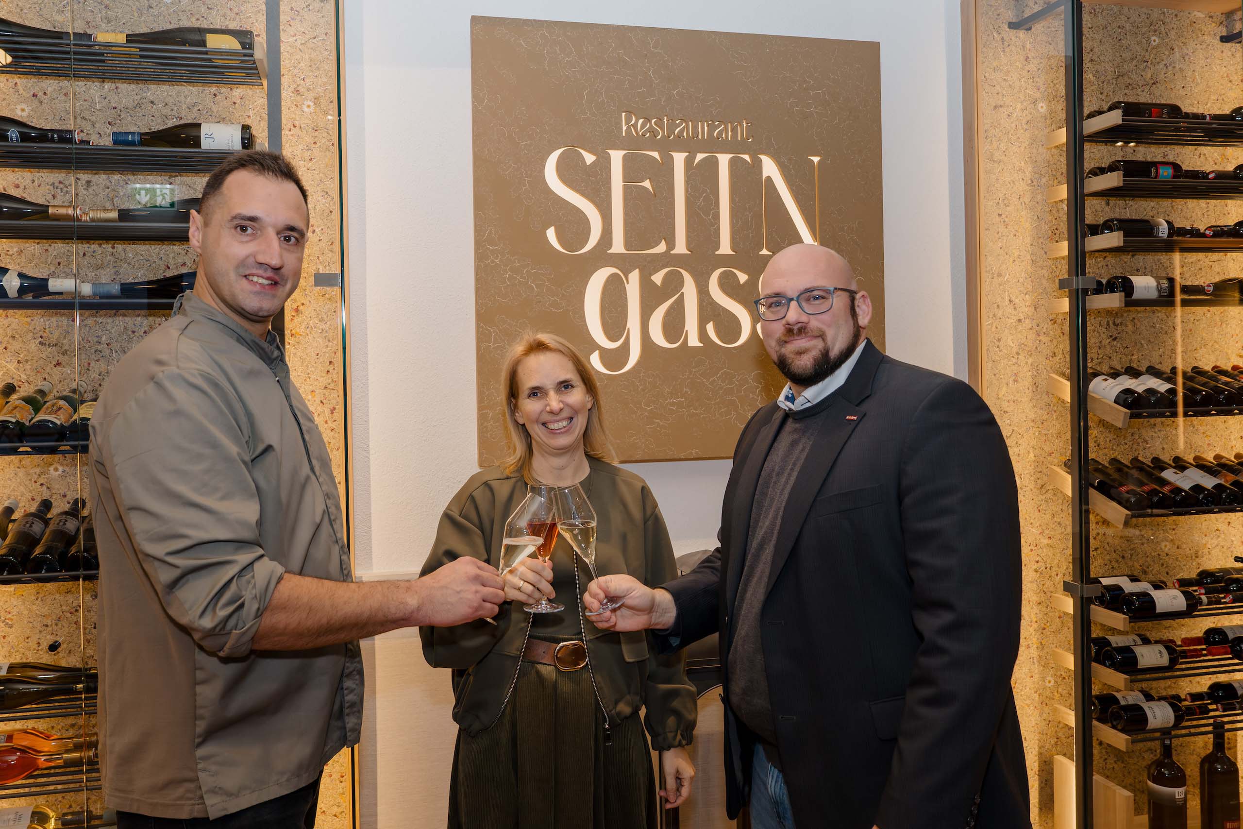 Drei Menschen stoßen mit Champagner in einem eleganten Restaurant an, ideal für Hochzeitsfeiern.