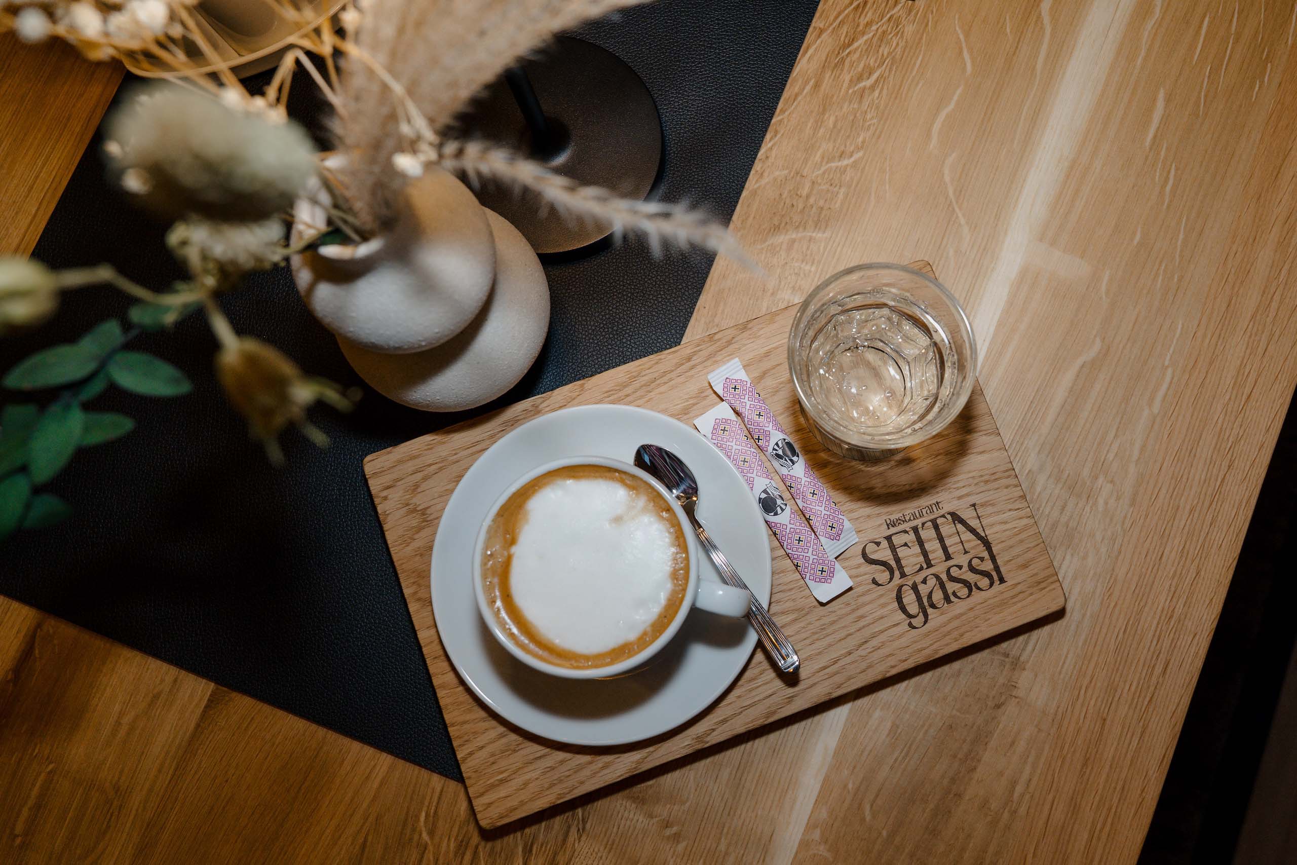 Kaffeegenuss und stilvolle Blumenarrangements auf einem Holztisch, perfekte Atmosphäre für eine romantische Hochzeitslocation.