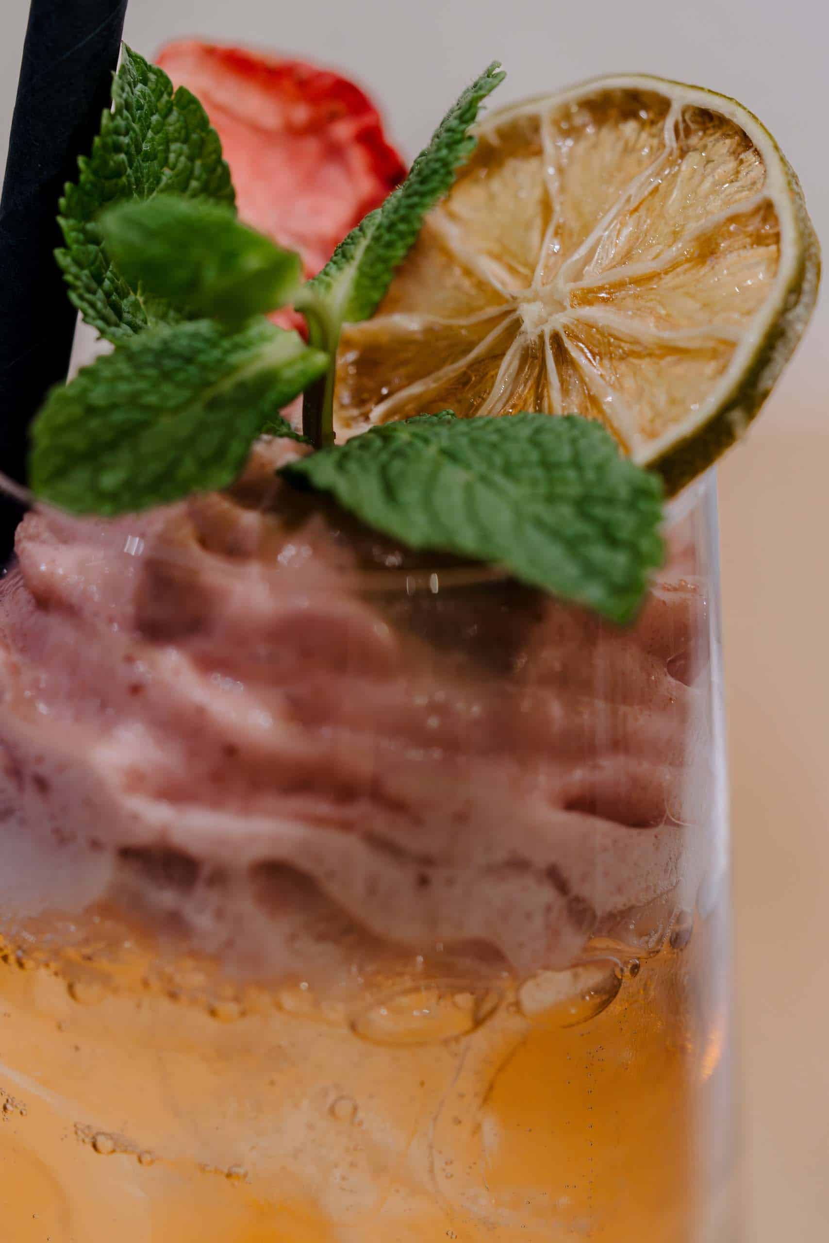 Erfrischender Hochzeitscocktail mit Minze, getrockneter Limette und Beeren, perfekt für eine stilvolle Traumhochzeitslocation.