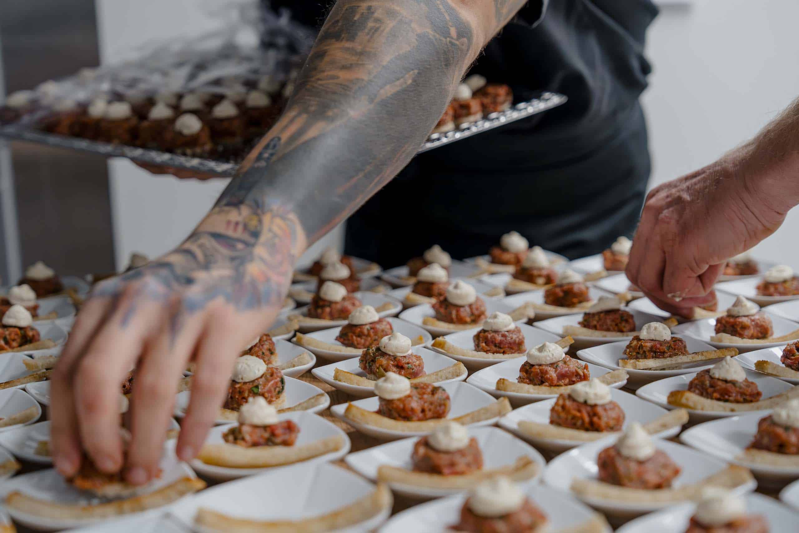 Hochzeitscatering: Köstliche Appetizer auf kleinen Tellern werden liebevoll für eine elegante Hochzeitsfeier vorbereitet.