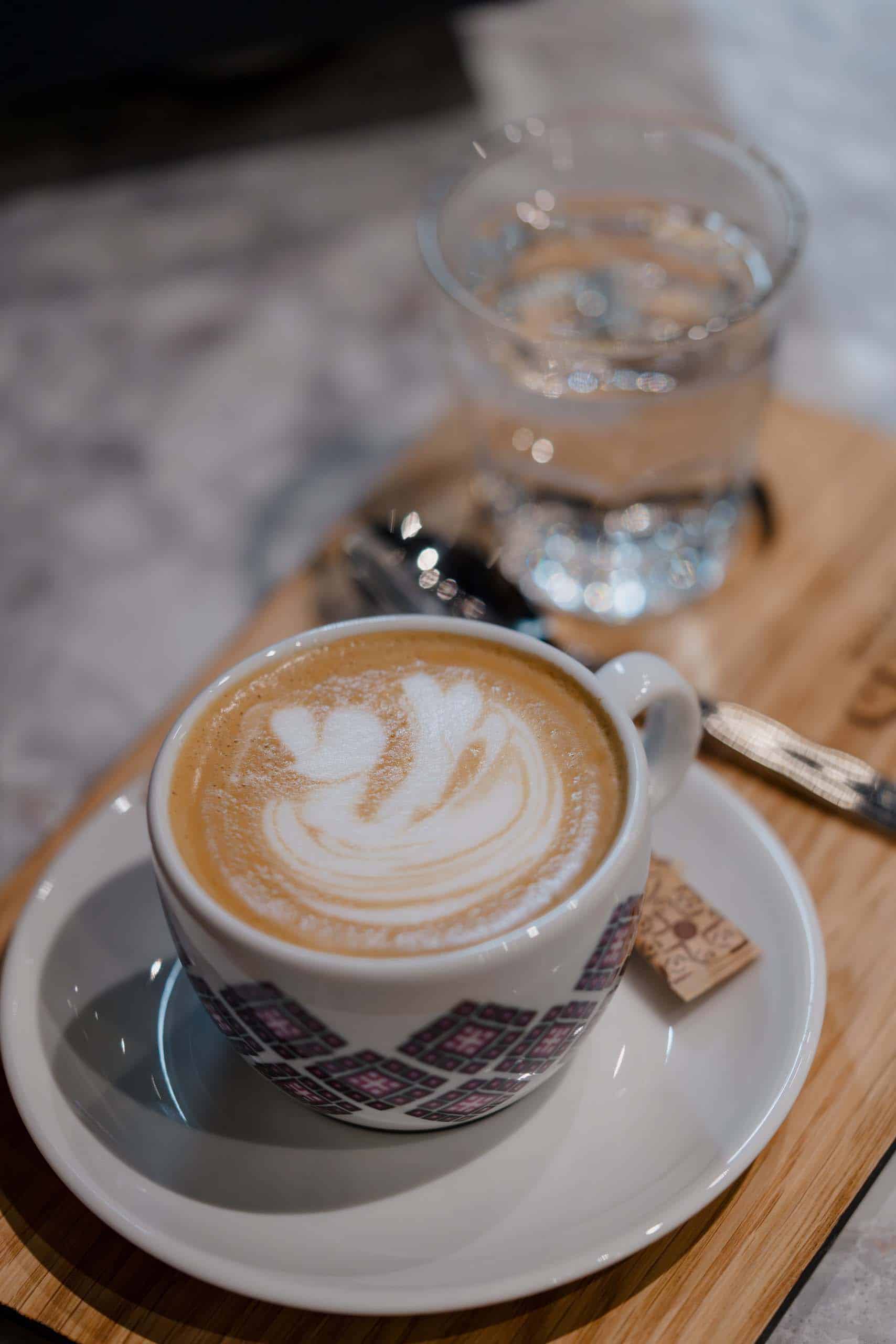Ein Cappuccino mit Herz Latte Art auf Holztisch, romantisches Hochzeitsfrühstück in einer stilvollen Location.