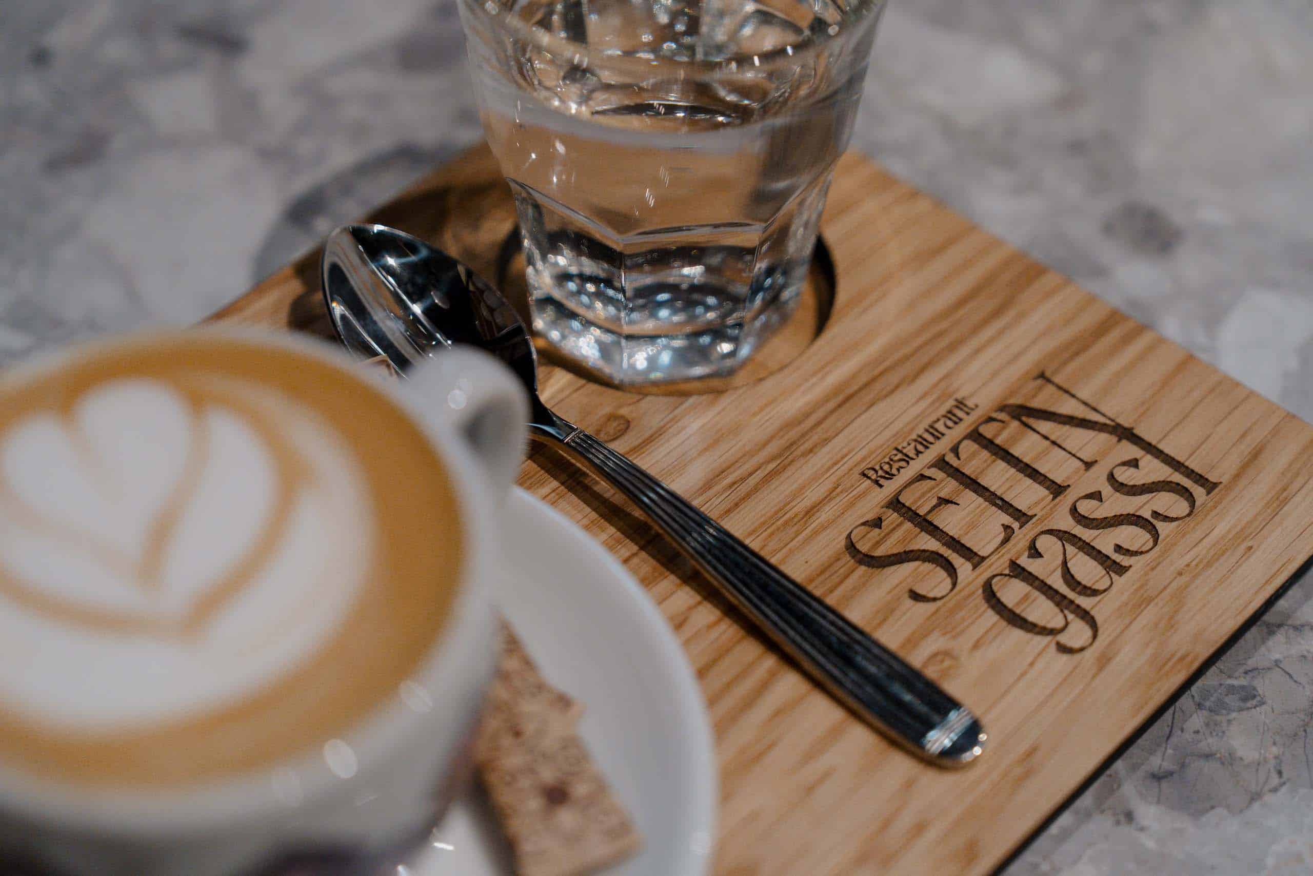 Cappuccino und Wasser auf Bambusbrett in stilvoller Hochzeitslocation, ideal für romantische Feiern im Restaurant Settingassi.