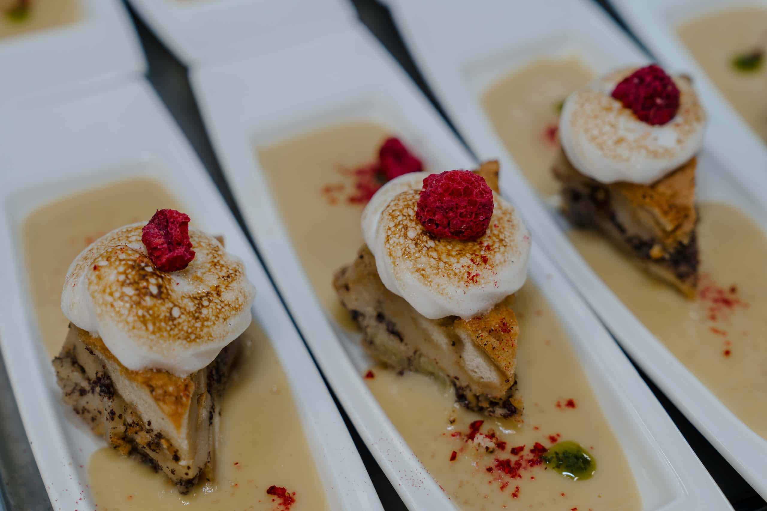 Elegantes Dessert mit Himbeere und Baiser auf cremiger Soße, ideal für Hochzeitsfeiern in exklusiver Location.