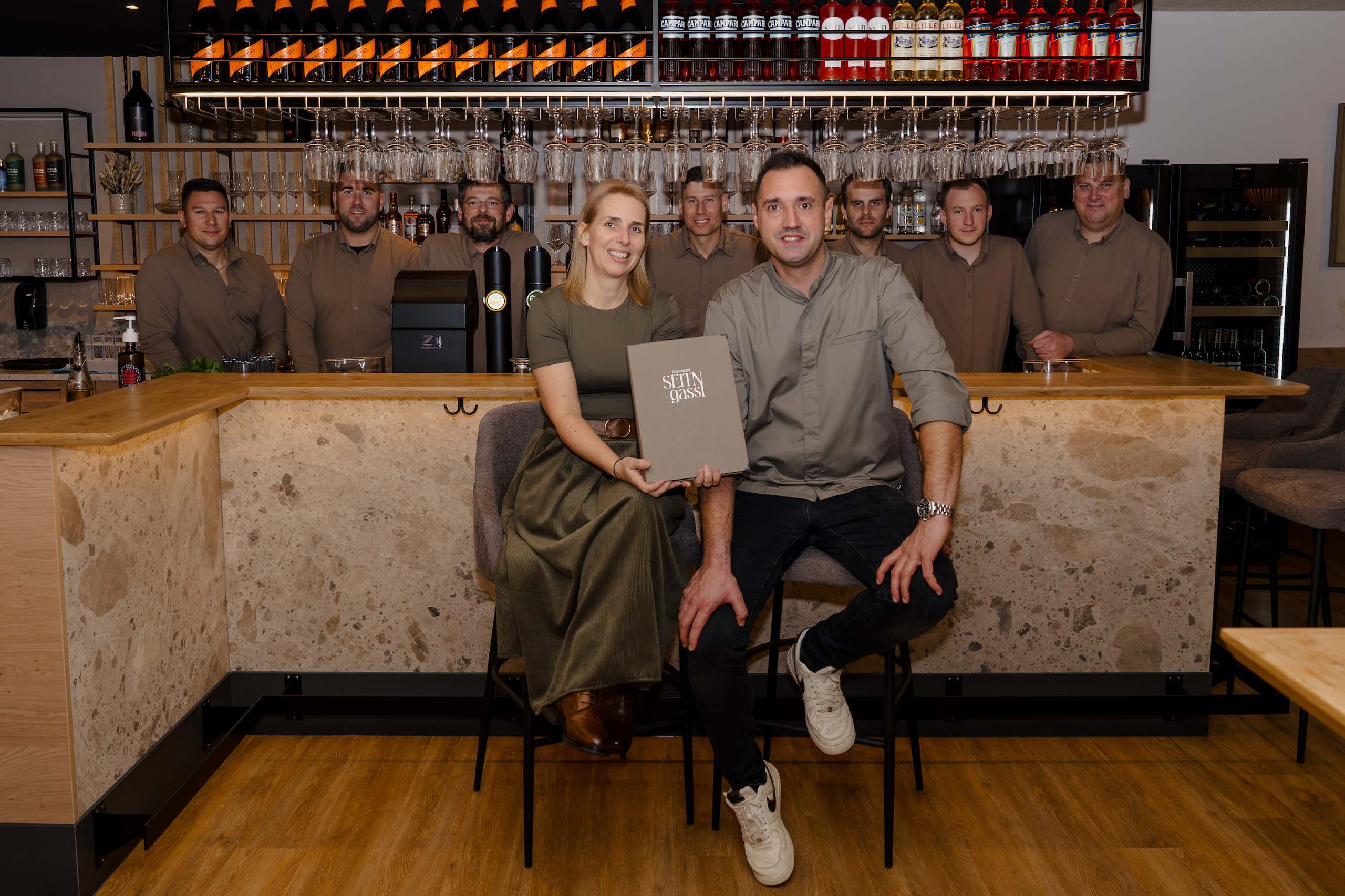 Paar präsentiert Hochzeitslocation in stilvoller Bar, ideal für den Hochzeitstraum bei Stern Gassl mit freundlichem Team.