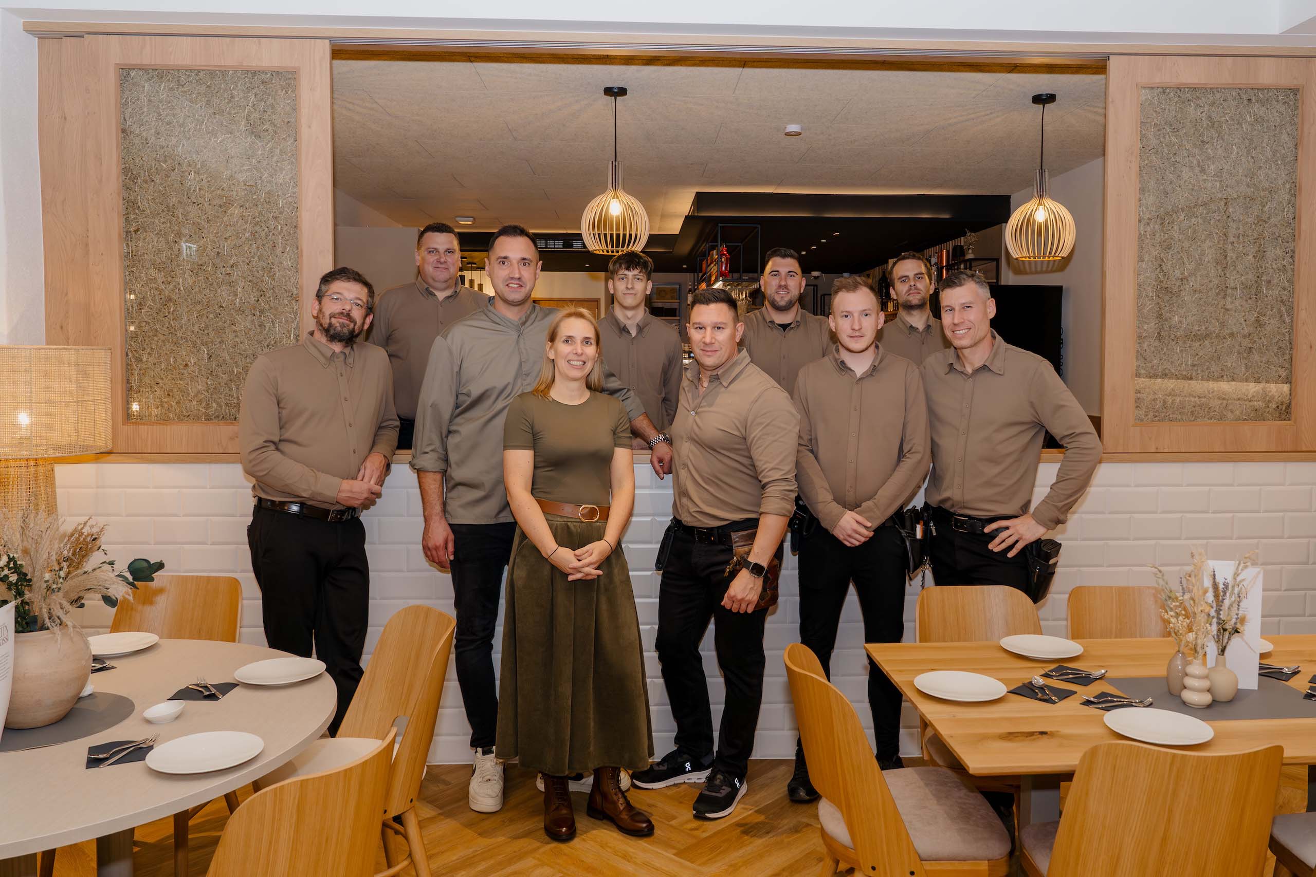 Das Team einer eleganten Hochzeitslocation steht lächelnd in einem stilvoll dekorierten Raum gemeinsam für ein Foto.