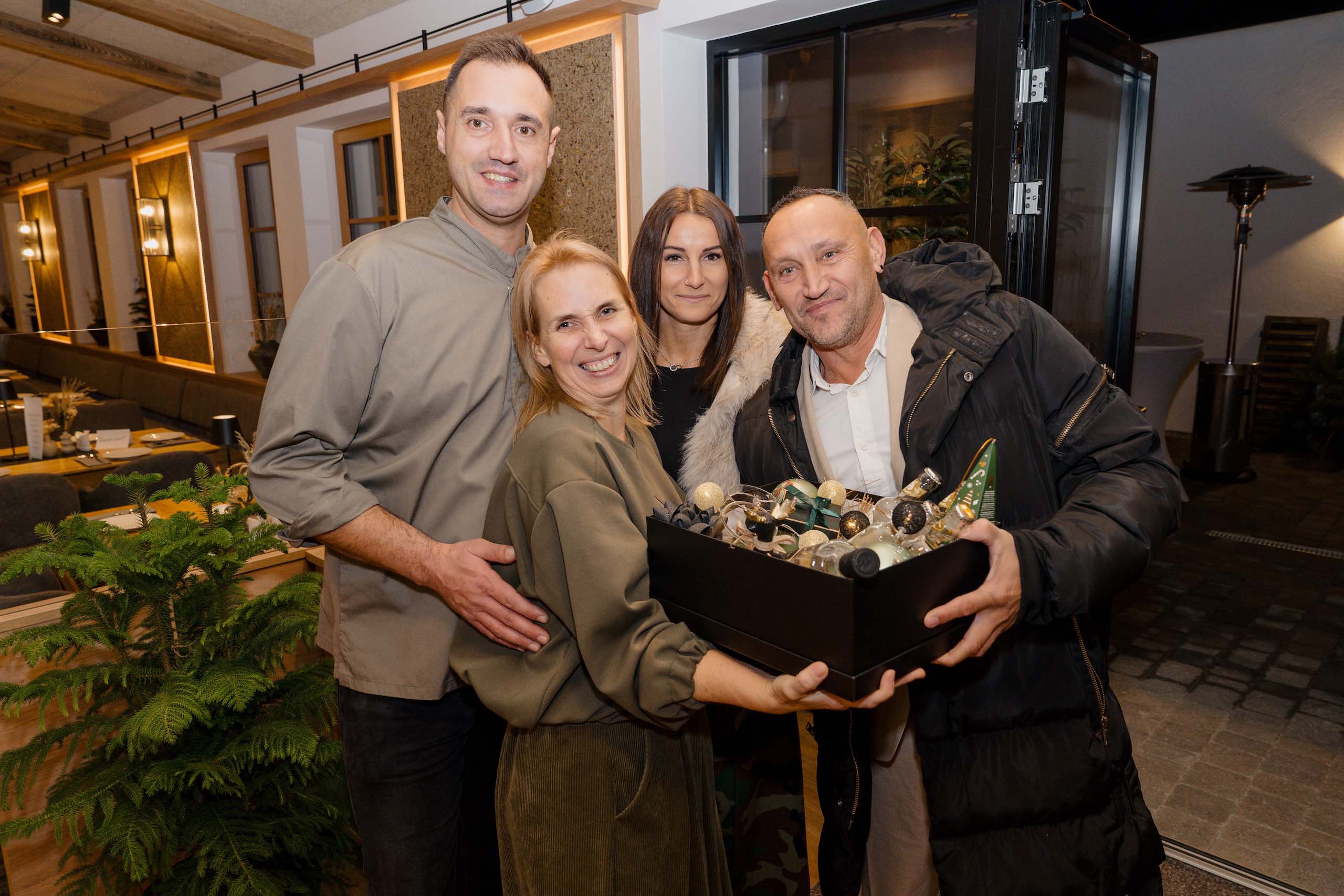 Vier fröhliche Menschen halten eine dekorative Box in moderner Hochzeitslocation, perfekt für den Hochzeitstraum.