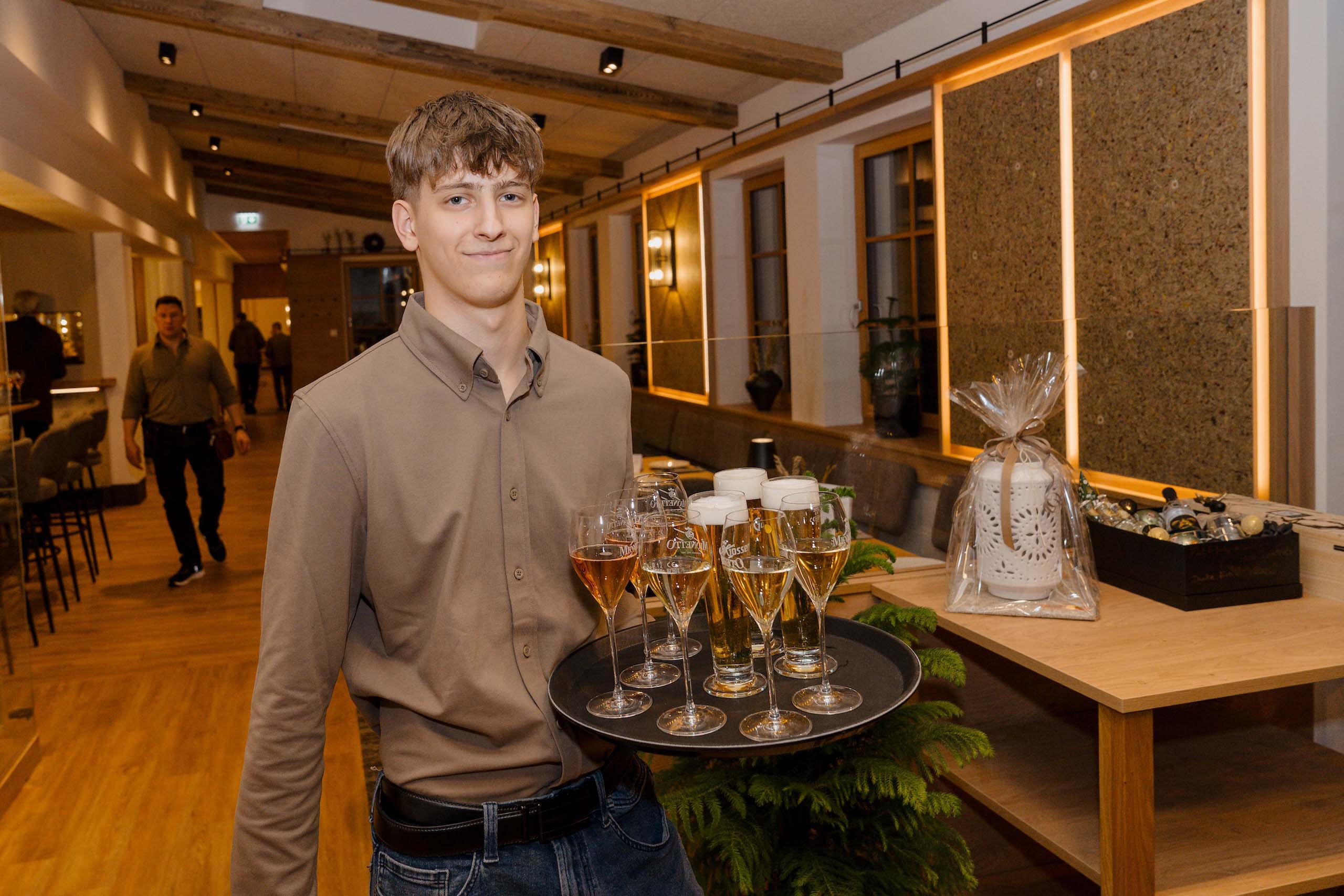 Kellner serviert Sekt und Bier in eleganter Hochzeitslocation mit Holzdekor, ideal für den besonderen Hochzeitstraum.
