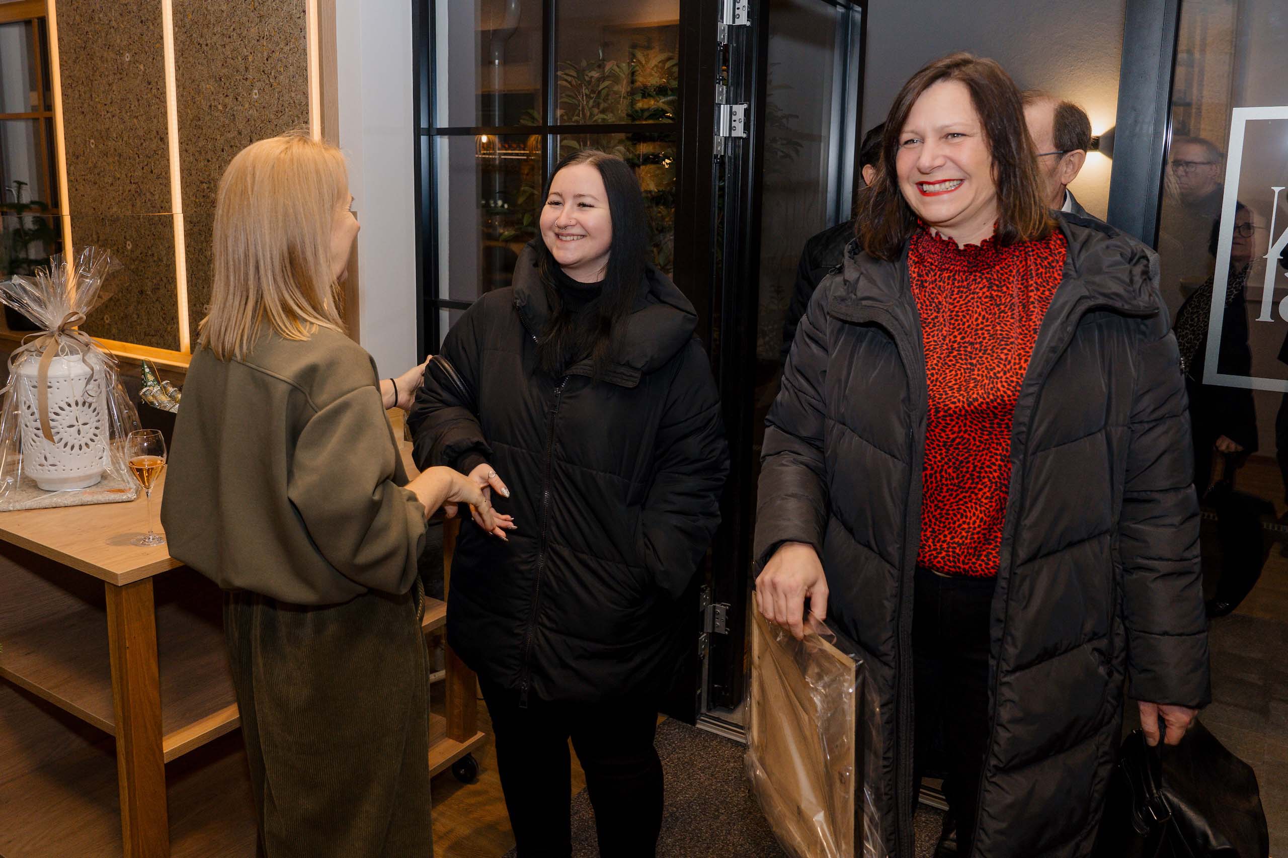 Drei lächelnde Frauen in einer Hochzeitslocation tauschen sich aus, einladende Atmosphäre für den Hochzeitstraum.
