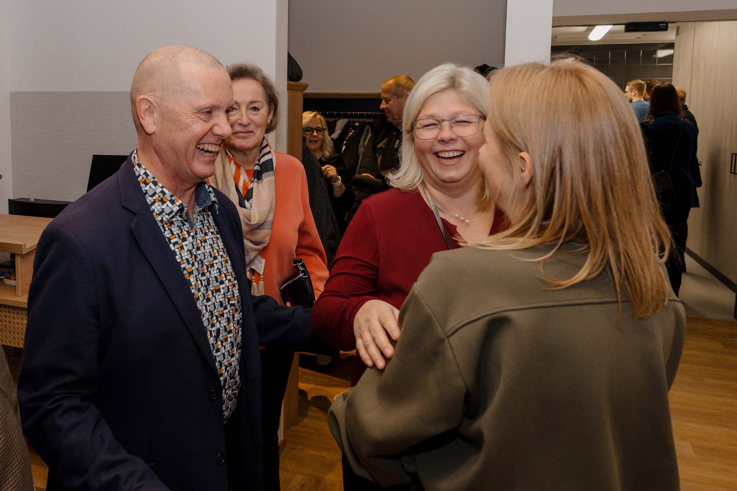 Eine Gruppe lächelnder Erwachsener unterhält sich fröhlich in einer eleganten Hochzeitslocation.