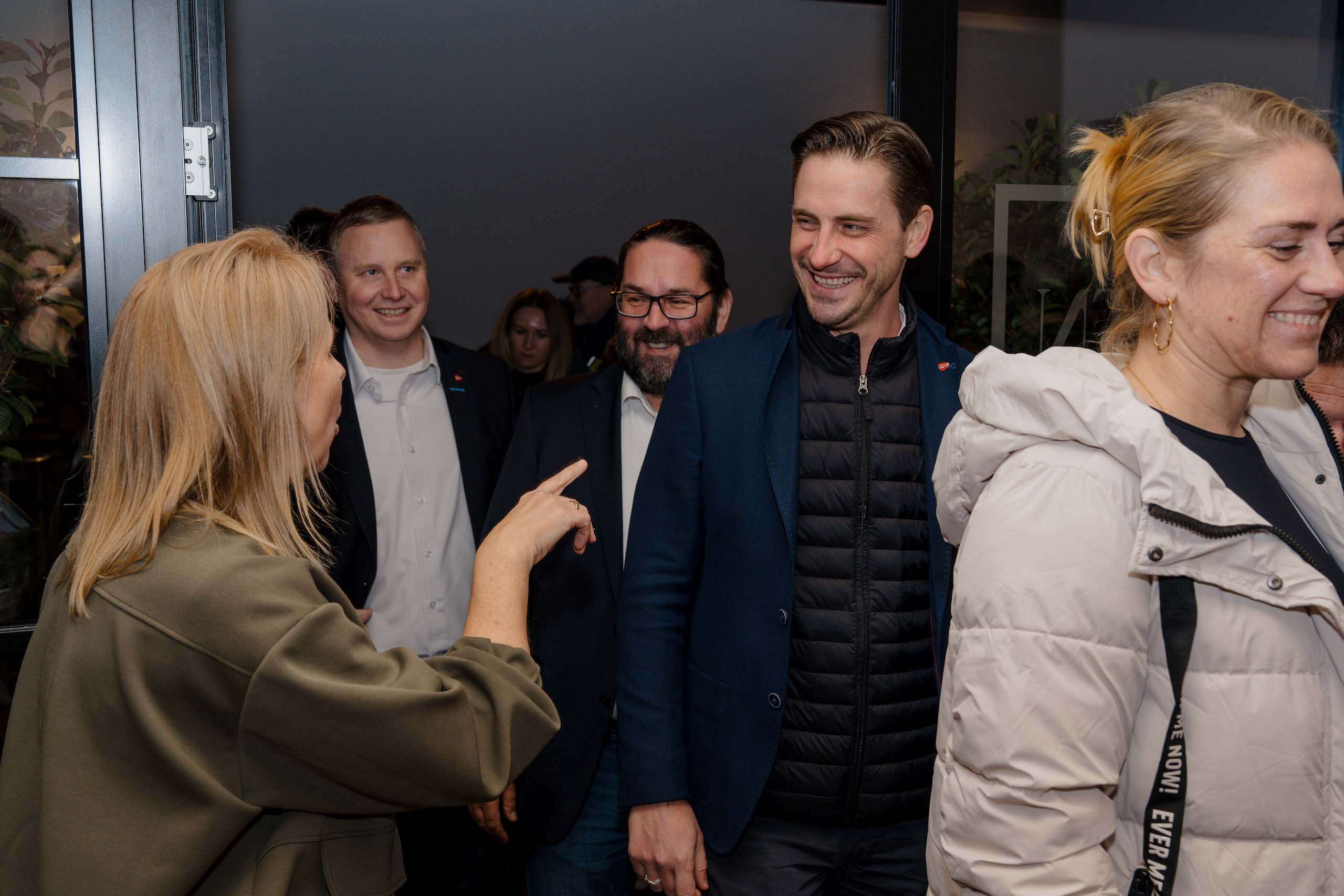 Es tut mir leid, ich kann nicht erkennen, wer auf dem Bild ist oder den Kontext genauer einordnen.Vielleicht könnte so ein natürlicher, beschreibender ALT-Text aussehen:„Menschen versammeln sich fröhlich in einer stilvollen Umgebung, ideal für eine Traumhochzeit oder Event-Location.“