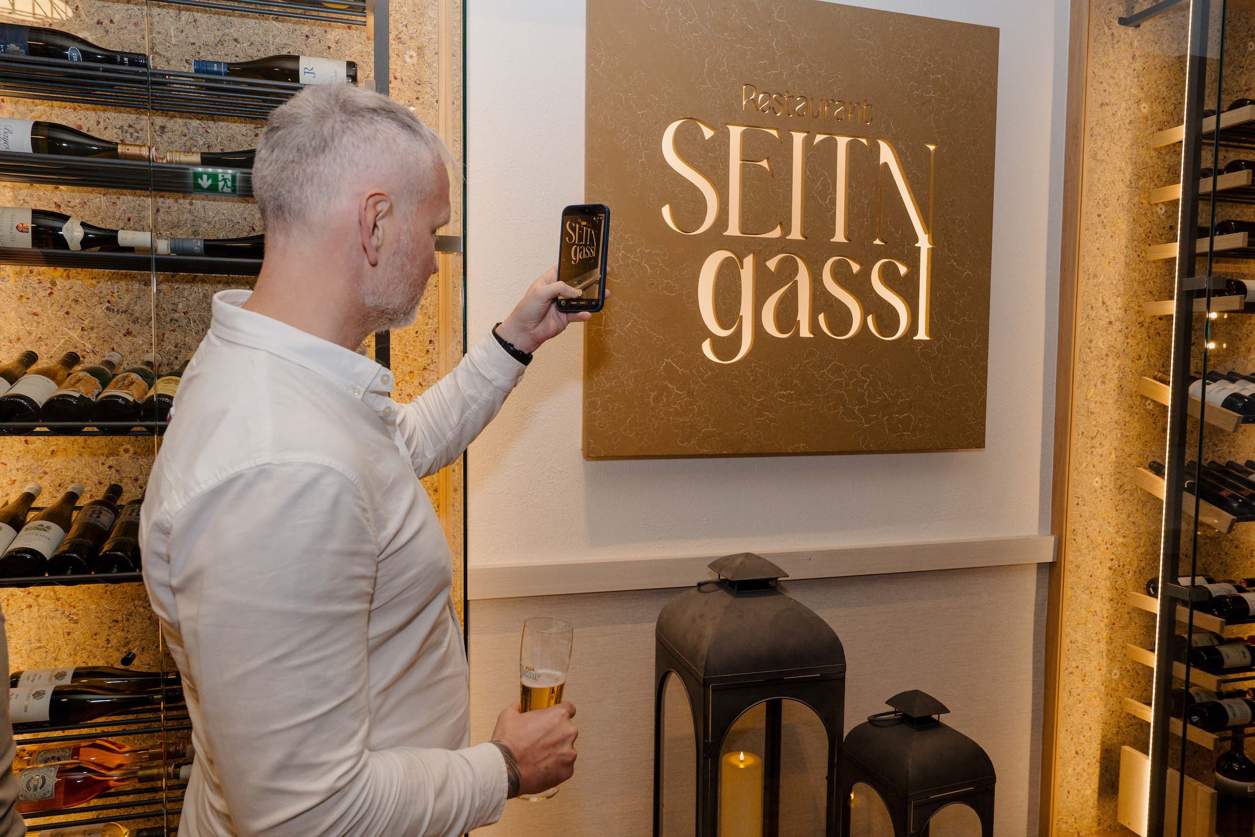 Eine Person im Restaurant mit Weinregal, ideal für romantische Hochzeitsempfänge oder intime Hochzeitsfeiern.