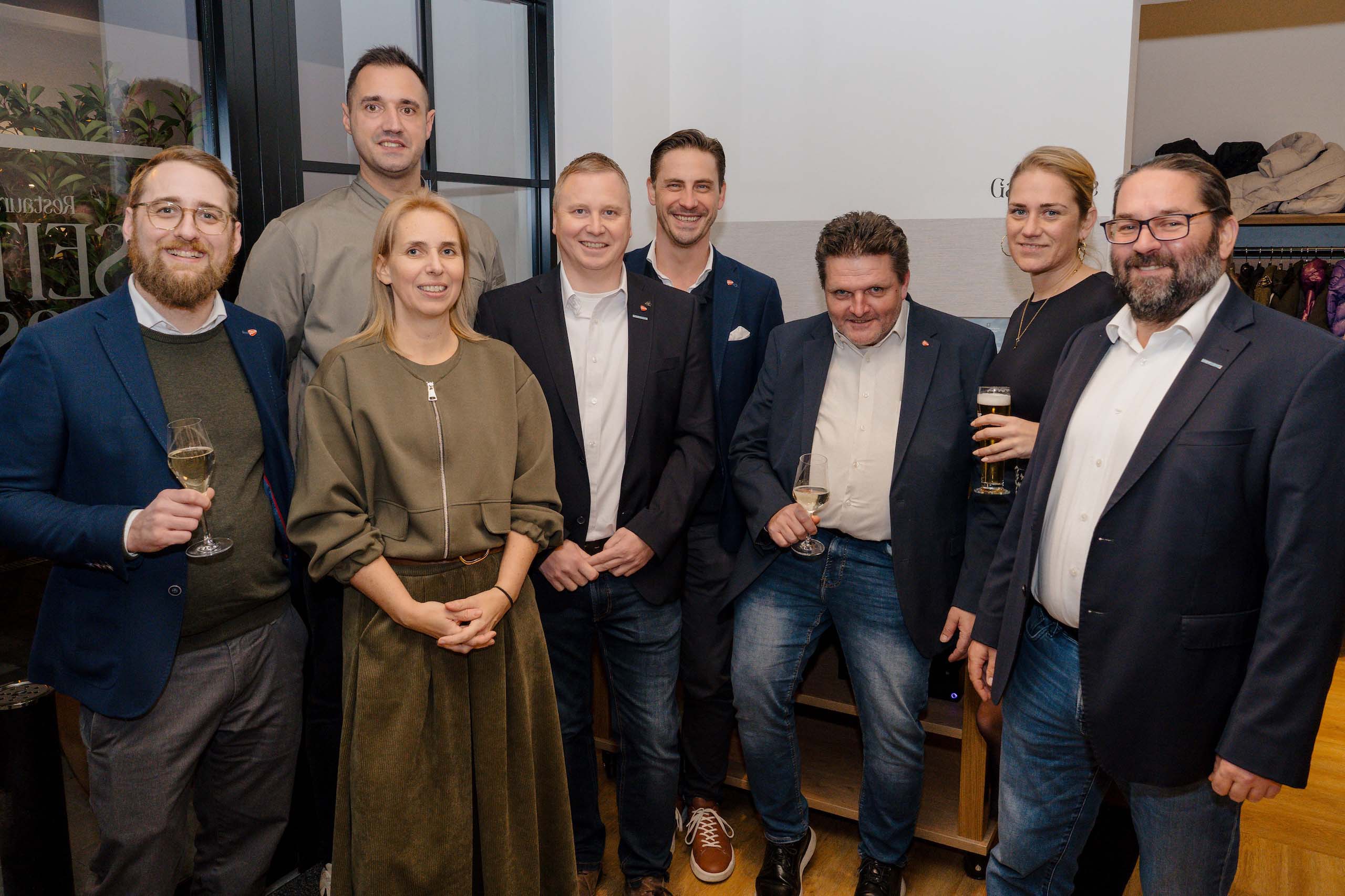 Gruppe von acht Personen in festlicher Kleidung bei einem Hochzeitsempfang in einer eleganten Hochzeitslocation.