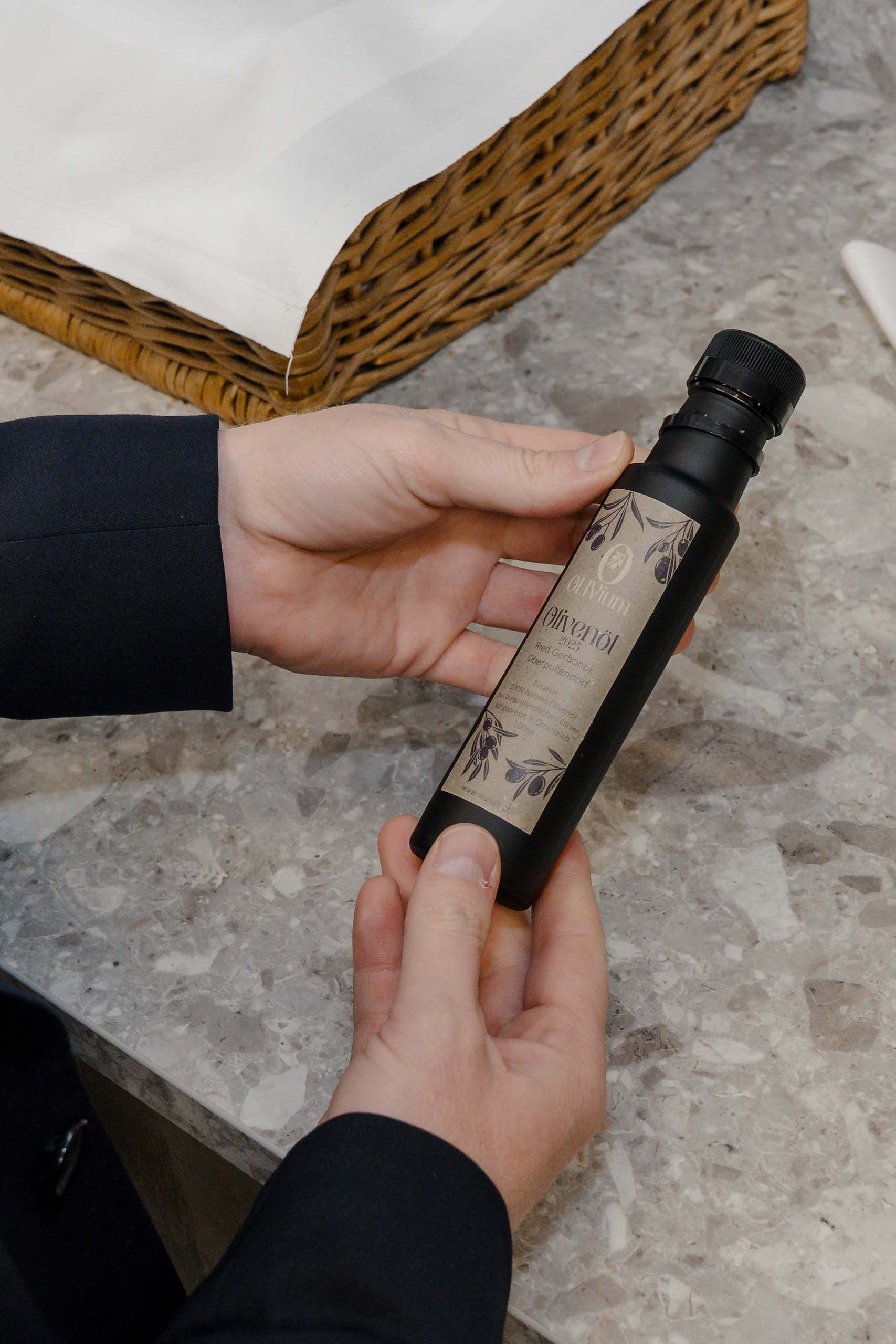 Elegante Hochzeitseinladung in Händen gehalten, auf einem Marmor-Tisch mit dekorativem Korb im Hintergrund.