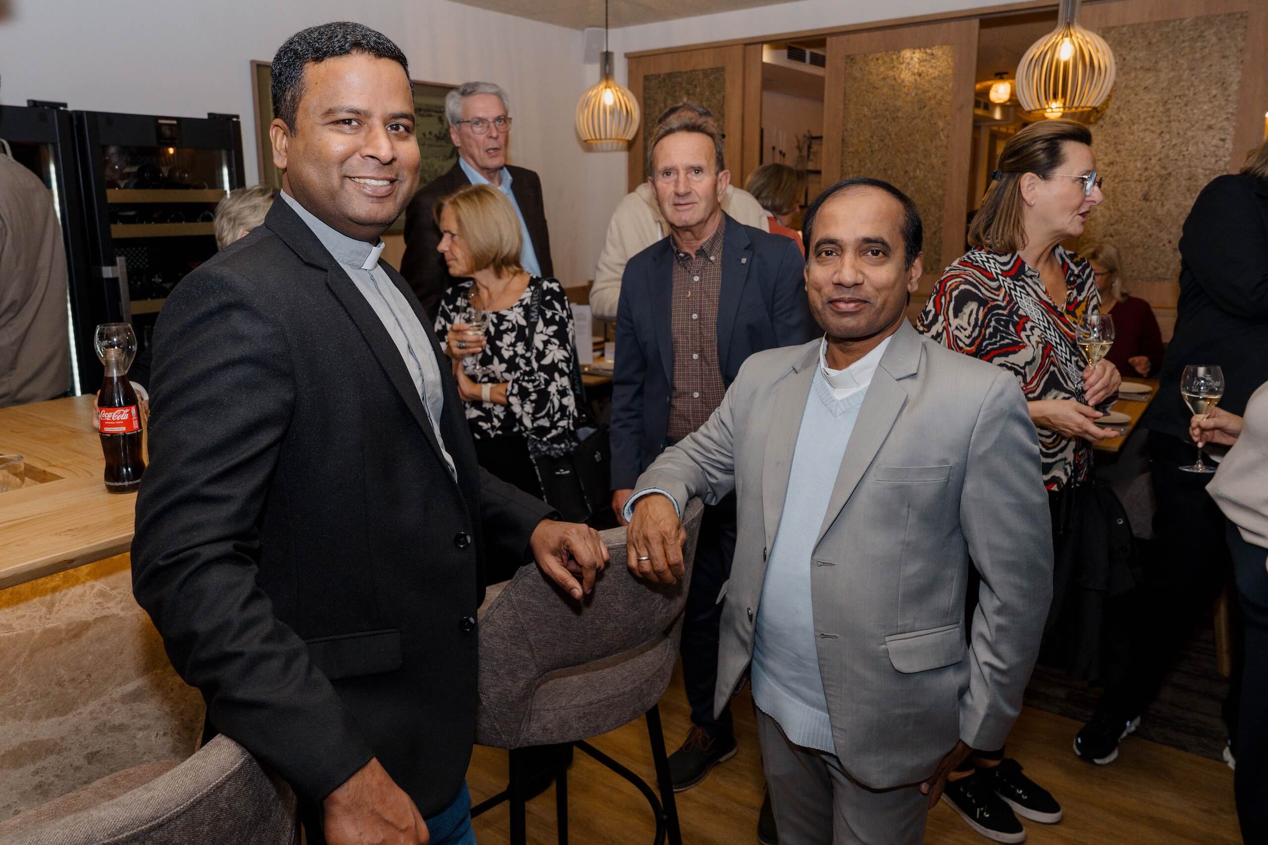 Gruppe elegant gekleideter Gäste bei einer Hochzeitsempfang im festlich dekorierten Raum, entspannte und fröhliche Stimmung.