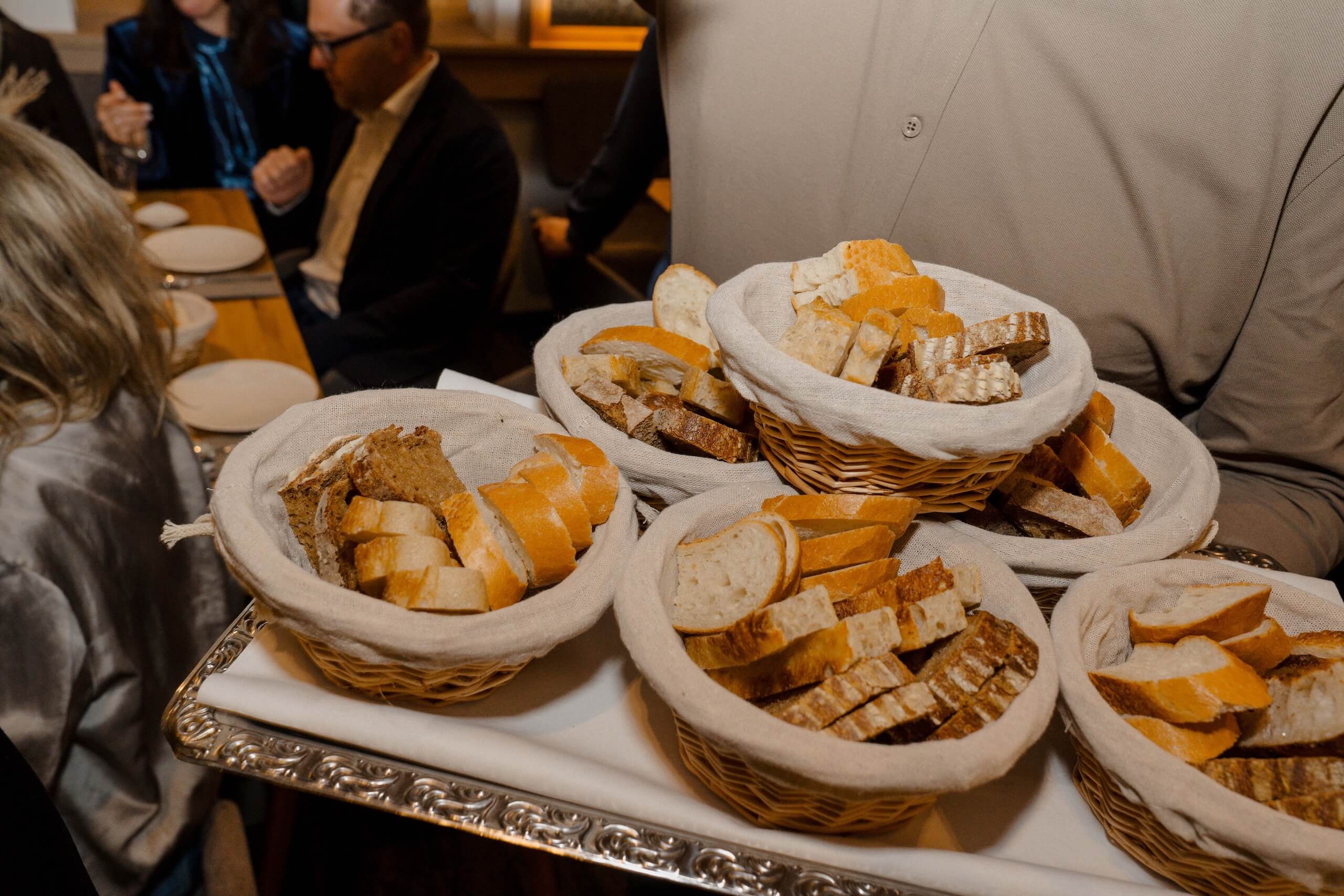 Körbe mit frischem Brot für Gäste einer eleganten Hochzeitsfeier, serviert auf stilvollen Tabletts in einer festlichen Location.
