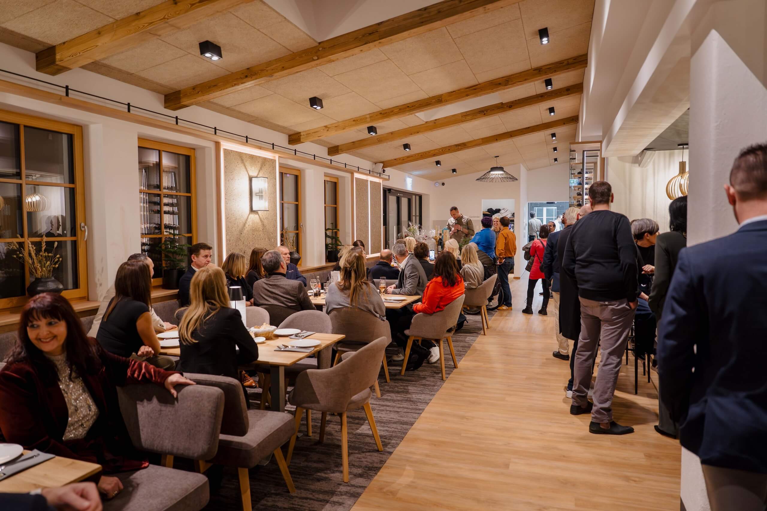 Eine elegante Hochzeitsgesellschaft genießt die stilvolle Atmosphäre einer modernen Hochzeitslocation mit Holzelementen.