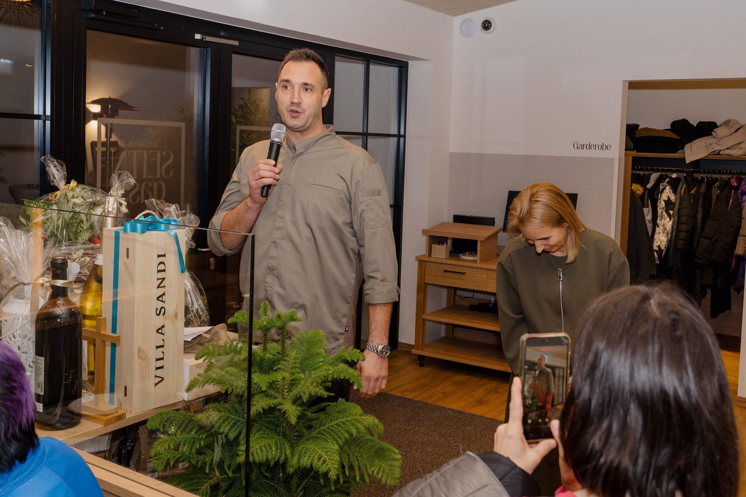 Ein Mann spricht auf einer Hochzeit, neben dekorativen Weinen, ideal für eine Hochzeitslocation voller Eleganz und Freude.