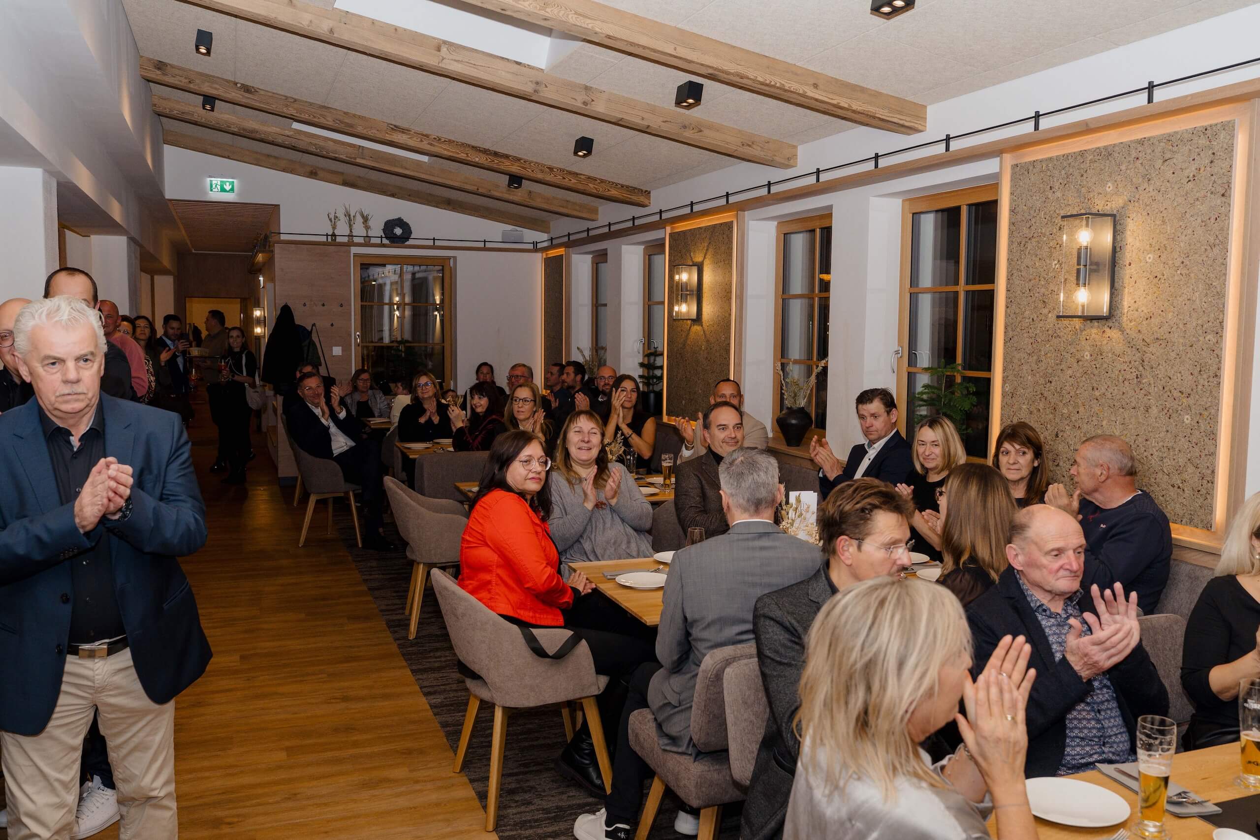 Gäste klatschen freudig bei einer festlichen Hochzeit in einer gemütlichen, rustikal gestalteten Hochzeitslocation.