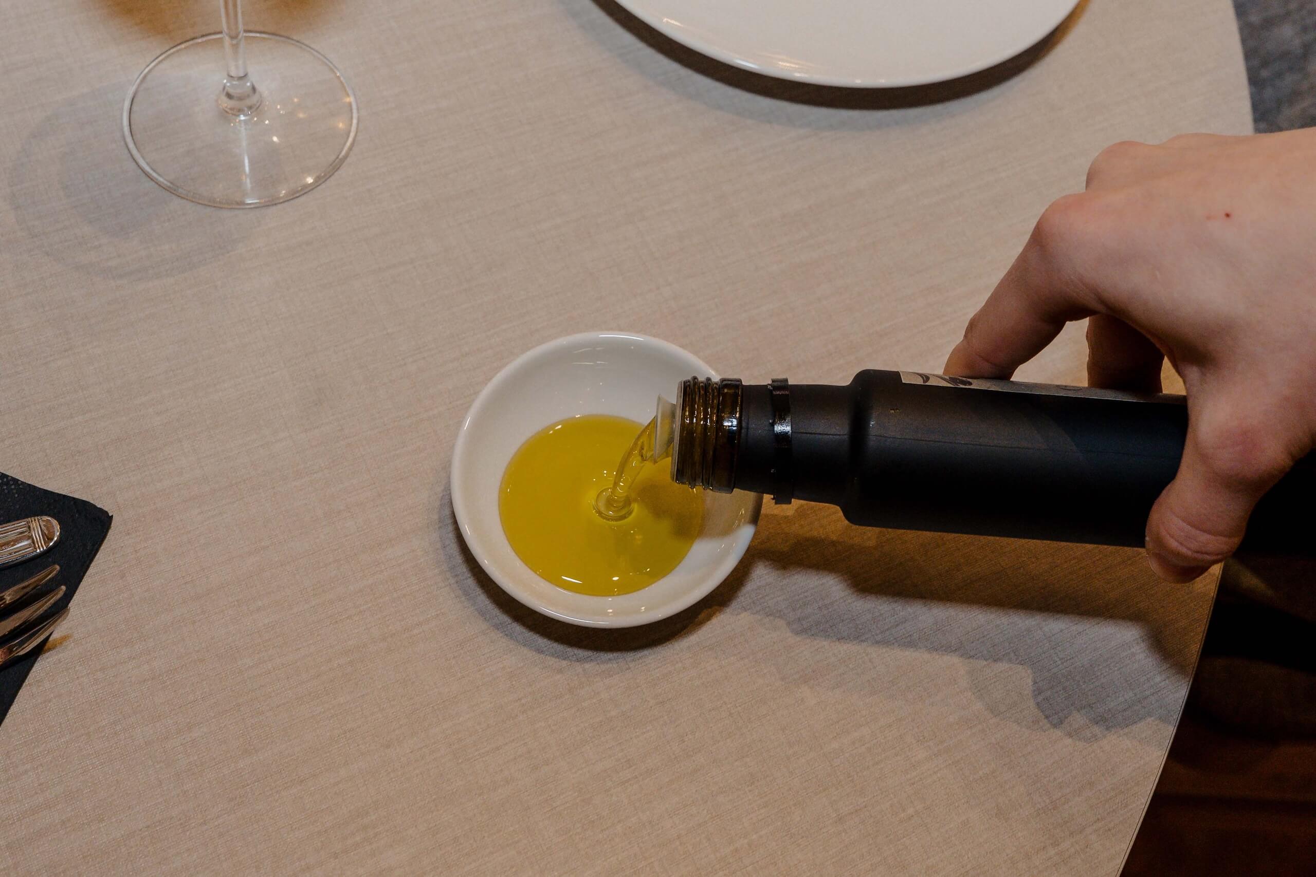 Hand gießt Öl in Schale auf Hochzeitstisch mit elegantem Besteck, perfekte Ergänzung für Hochzeitstraum-Dinner.