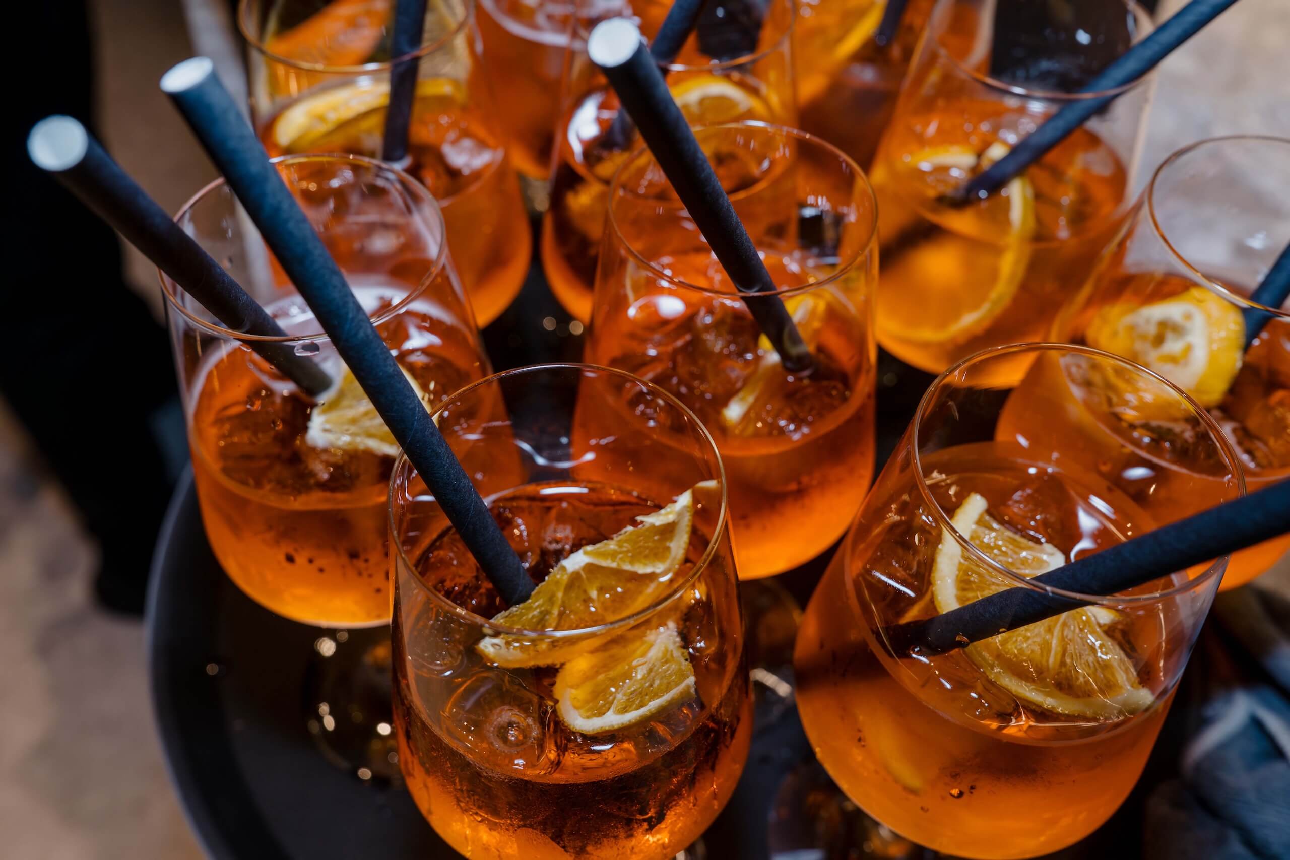 Erfrischende Aperol-Spritz-Cocktails mit Orangenscheiben auf Hochzeitsempfangstisch, perfekte Hochzeitslocation.