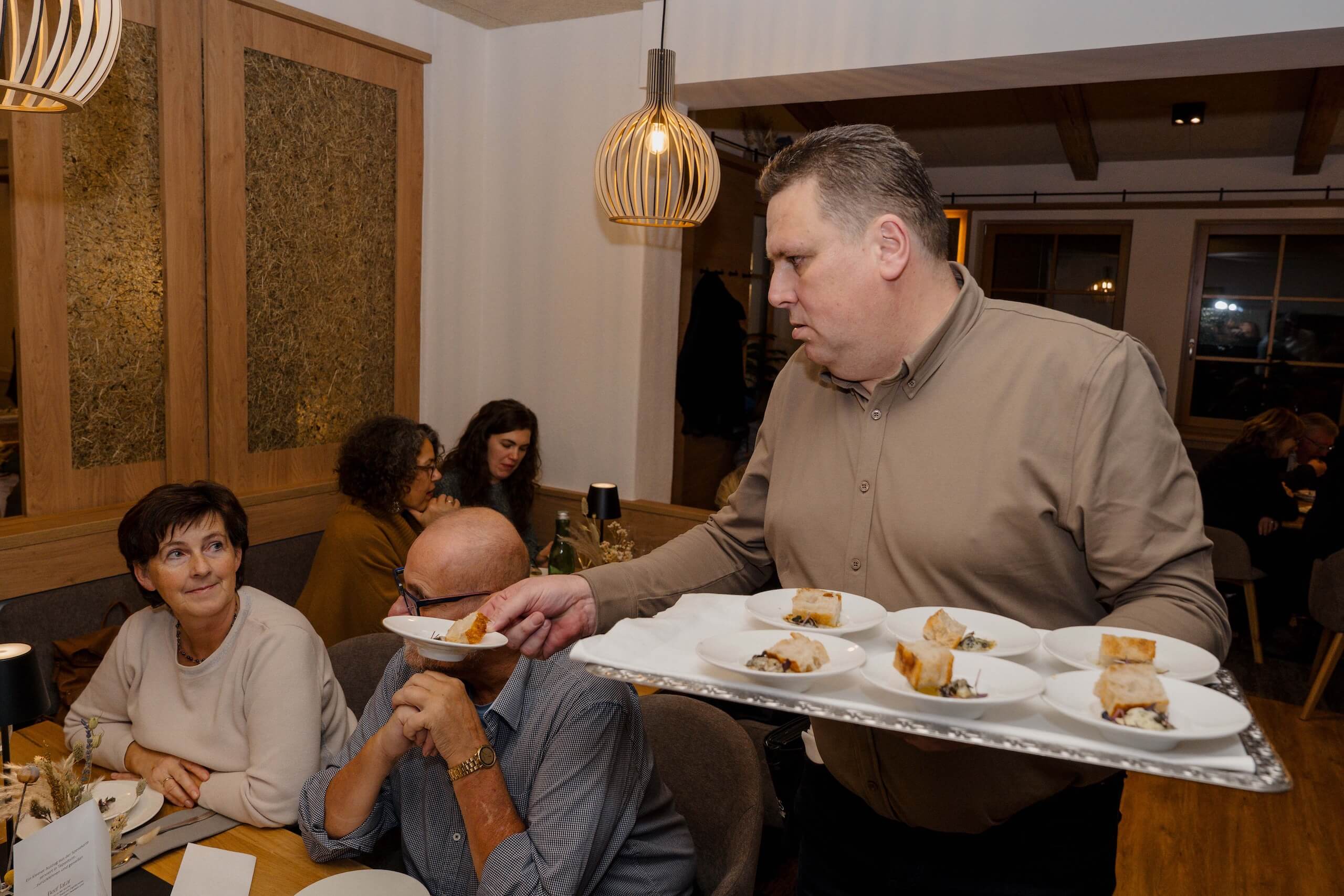 Kellner serviert elegante Vorspeisen bei einer Hochzeit, Gäste genießen stilvolle Atmosphäre in der Hochzeitslocation.
