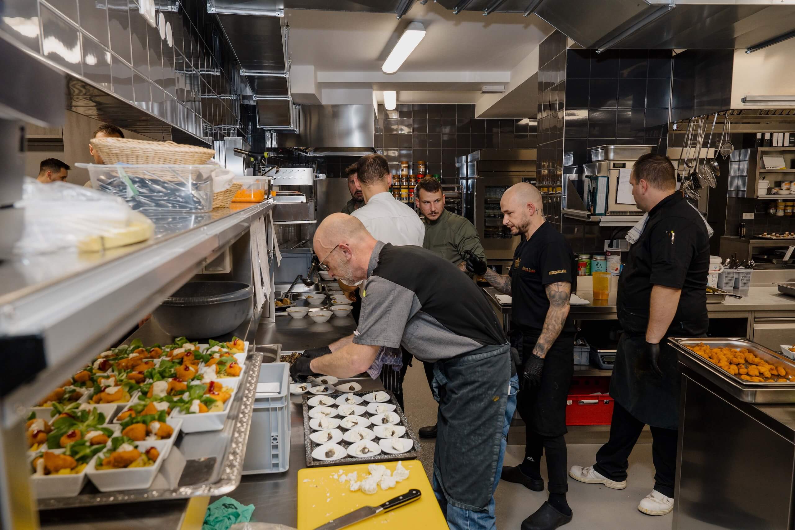 Küchenteam bereitet aufwendige Gerichte in moderner Hochzeitslocation vor, ideal für einen unvergesslichen Hochzeitstraum.