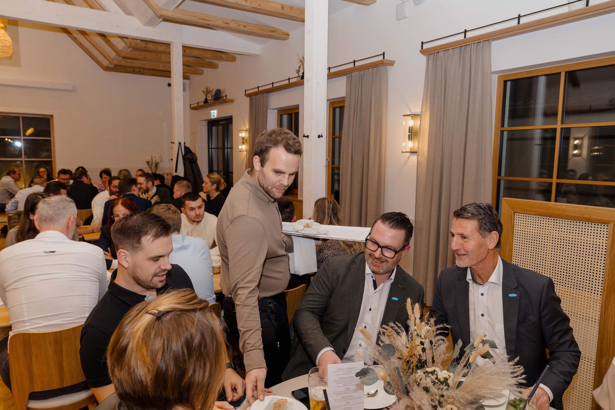 Elegante Hochzeitsgäste sitzen an stilvoll dekorierten Tischen in einem festlichen Saal und genießen die Atmosphäre der Feier.