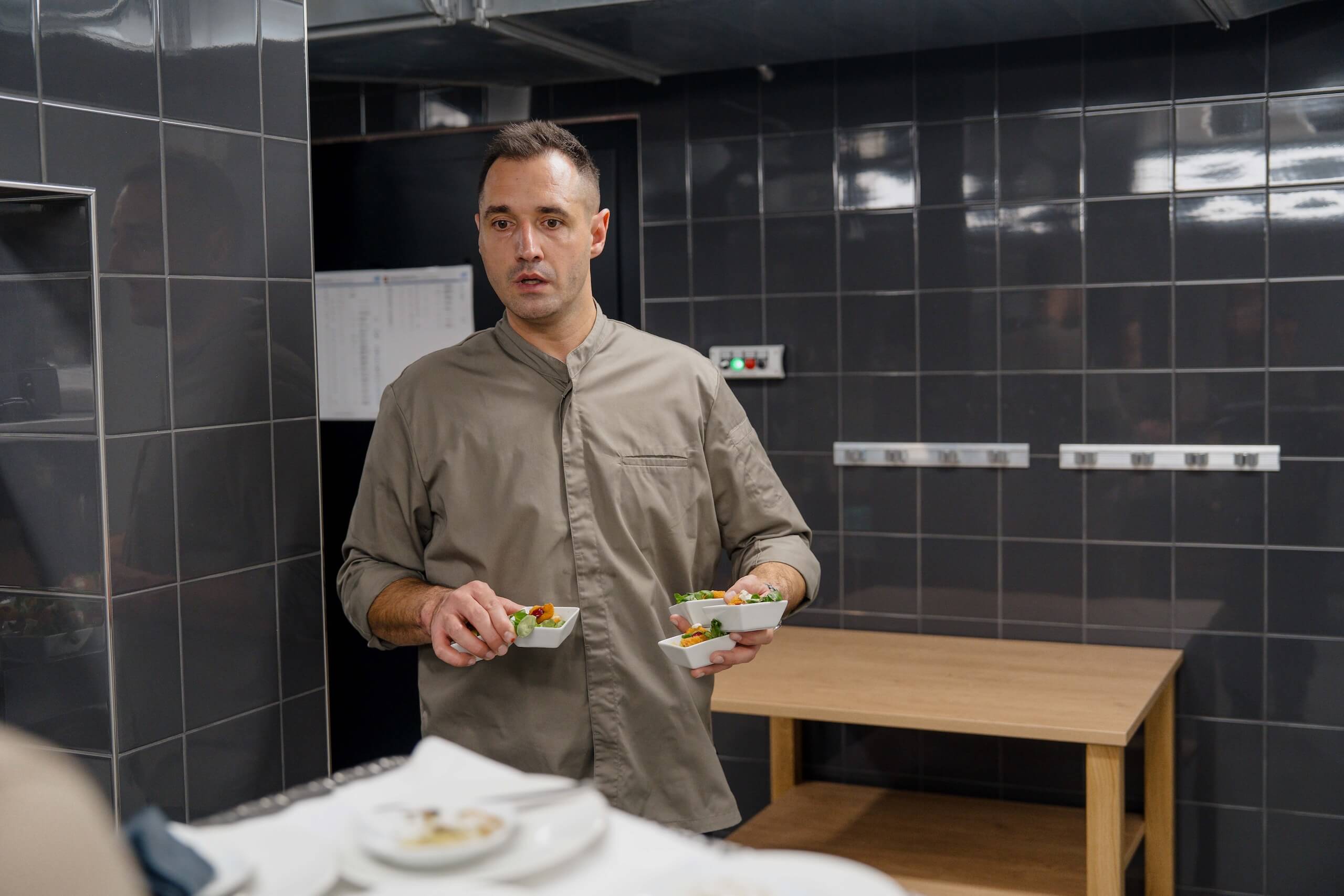 Koch in moderner Küche präsentiert stilvolle Vorspeisen für eine exklusive Hochzeitsfeier in traumhafter Location.