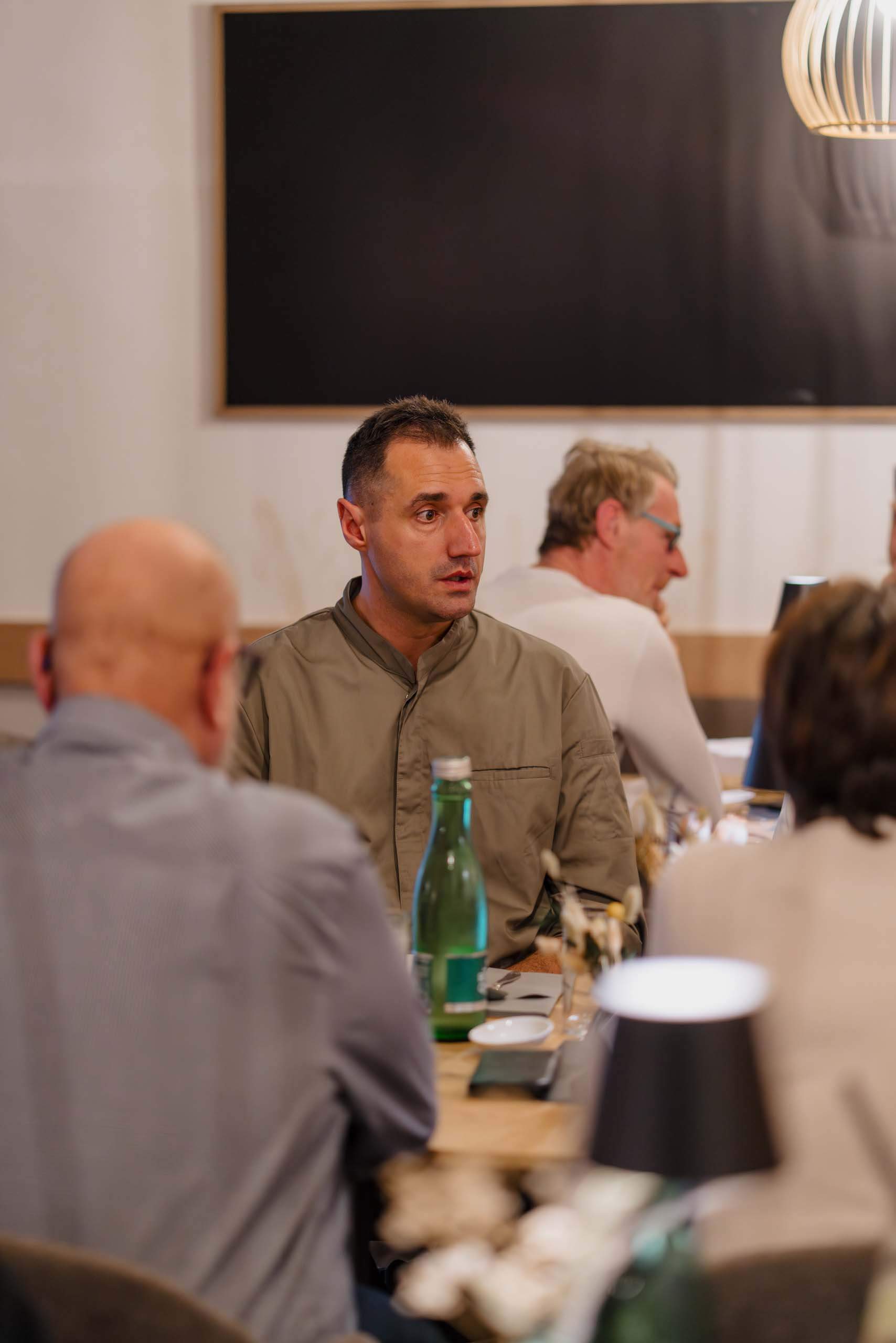 Ein Mann im Gespräch an einem Tisch bei einer Hochzeitsfeier in einer elegant dekorierten Location.