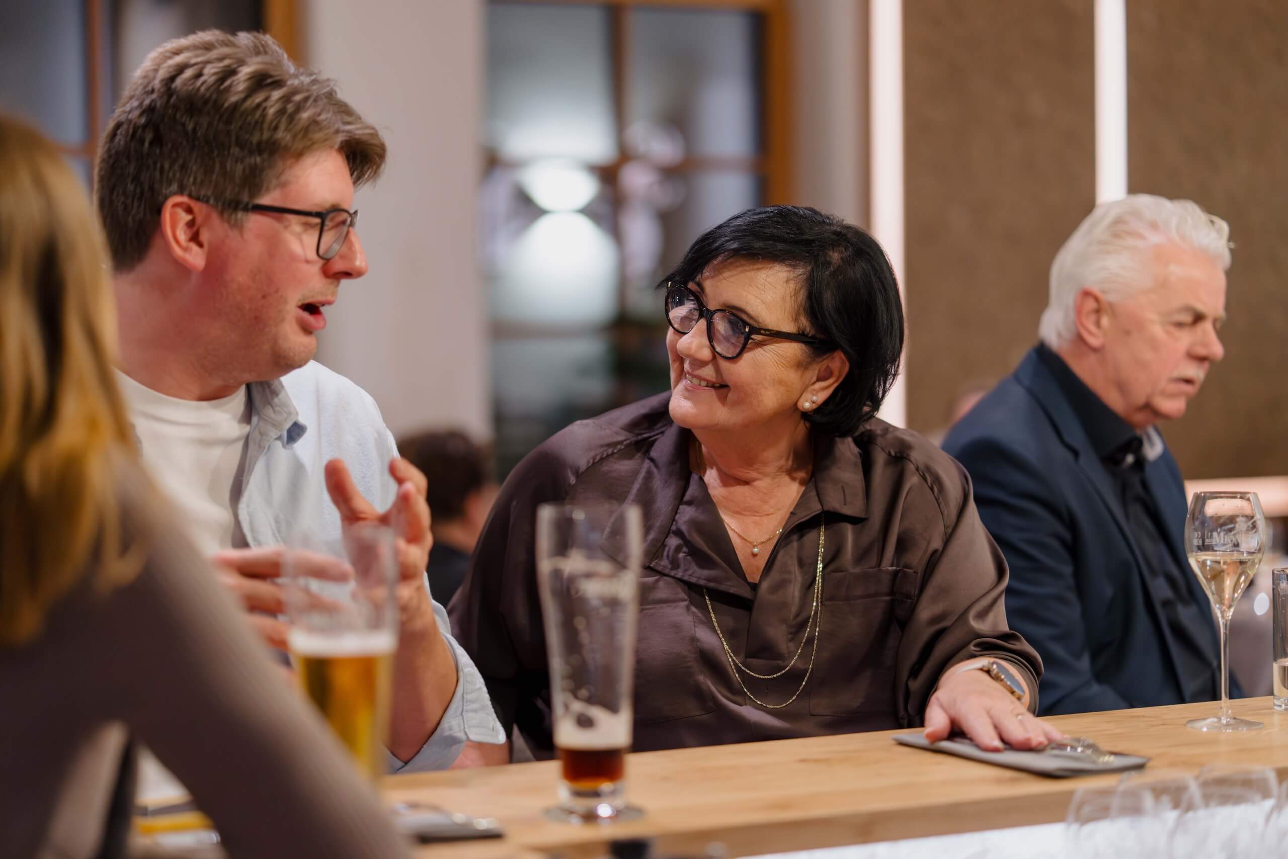 Gäste unterhalten sich lebhaft an der Bar einer eleganten Hochzeit, während festliche Stimmung den Raum erfüllt.