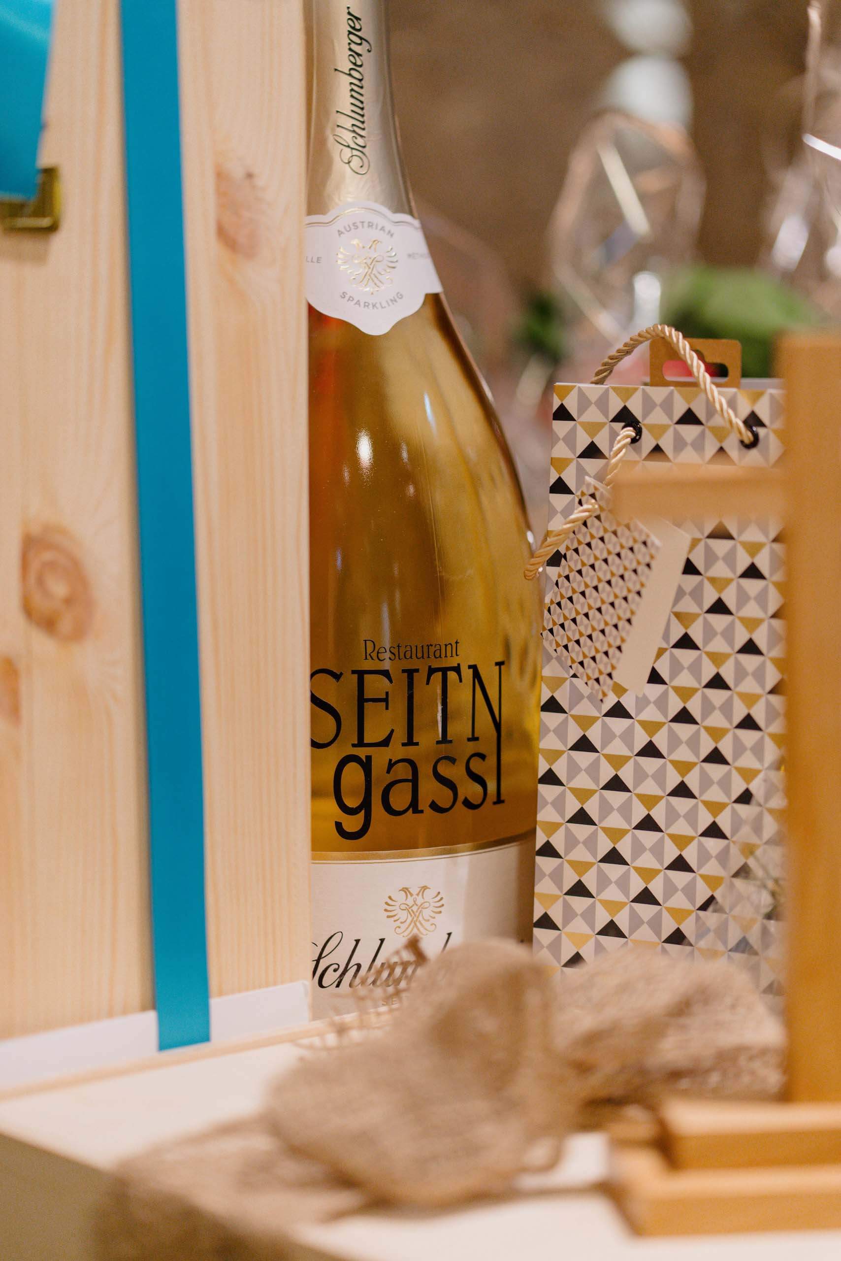 Elegante Hochzeitsdeko mit Sektflasche und Geschenkverpackung, ideal für eine traumhafte Hochzeitslocation.